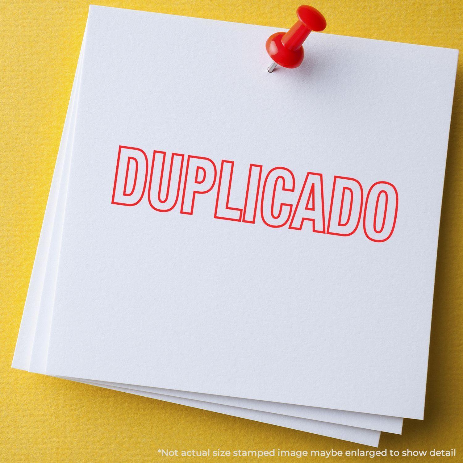 A stack of white papers with the word DUPLICADO stamped in red using the Duplicado Rubber Stamp, pinned with a red pushpin on a yellow surface.