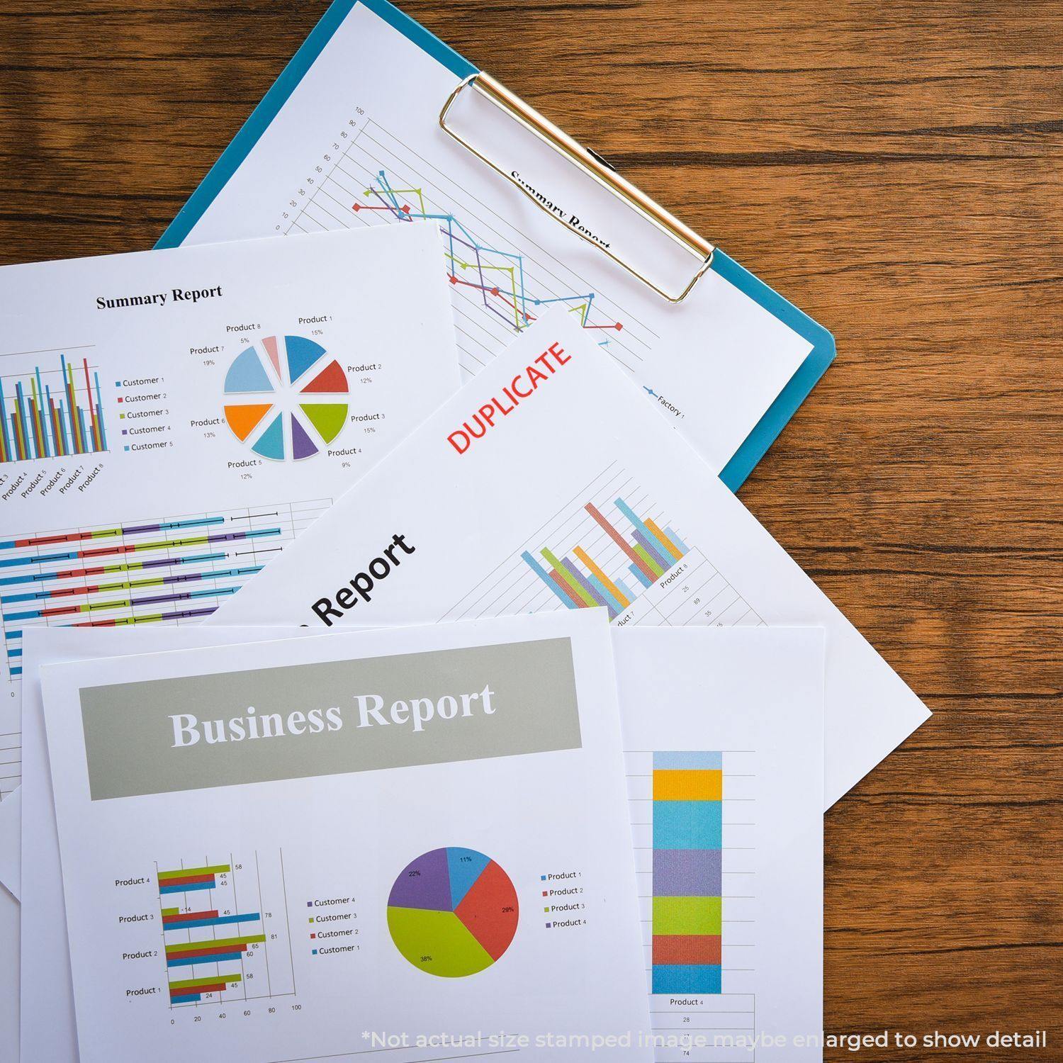 A Large Self Inking Duplicate Stamp marks DUPLICATE in red on various business reports and charts on a wooden desk.