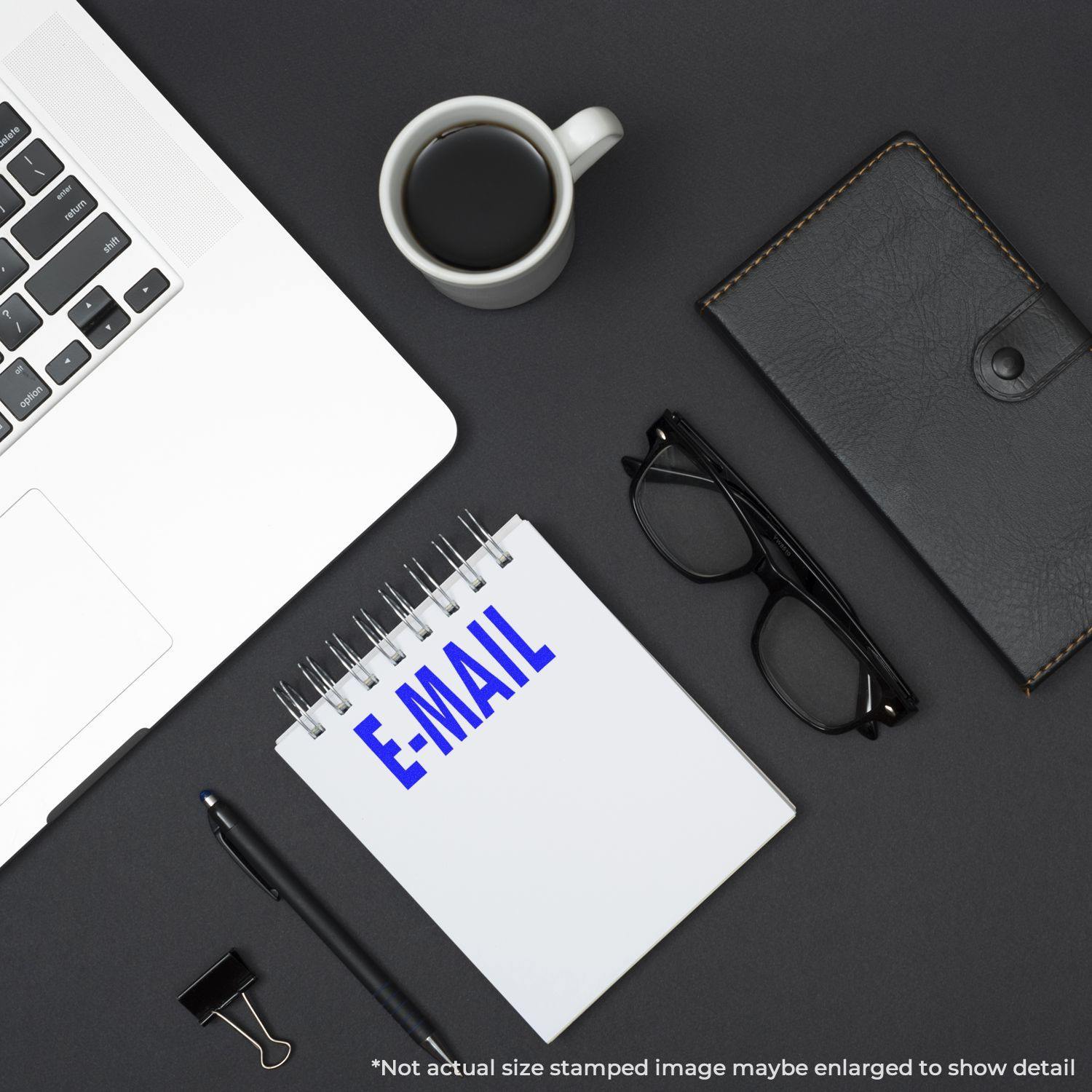 A desk with a laptop, coffee, glasses, notebook stamped with E-MAIL using the E Mail Rubber Stamp, and a leather wallet.