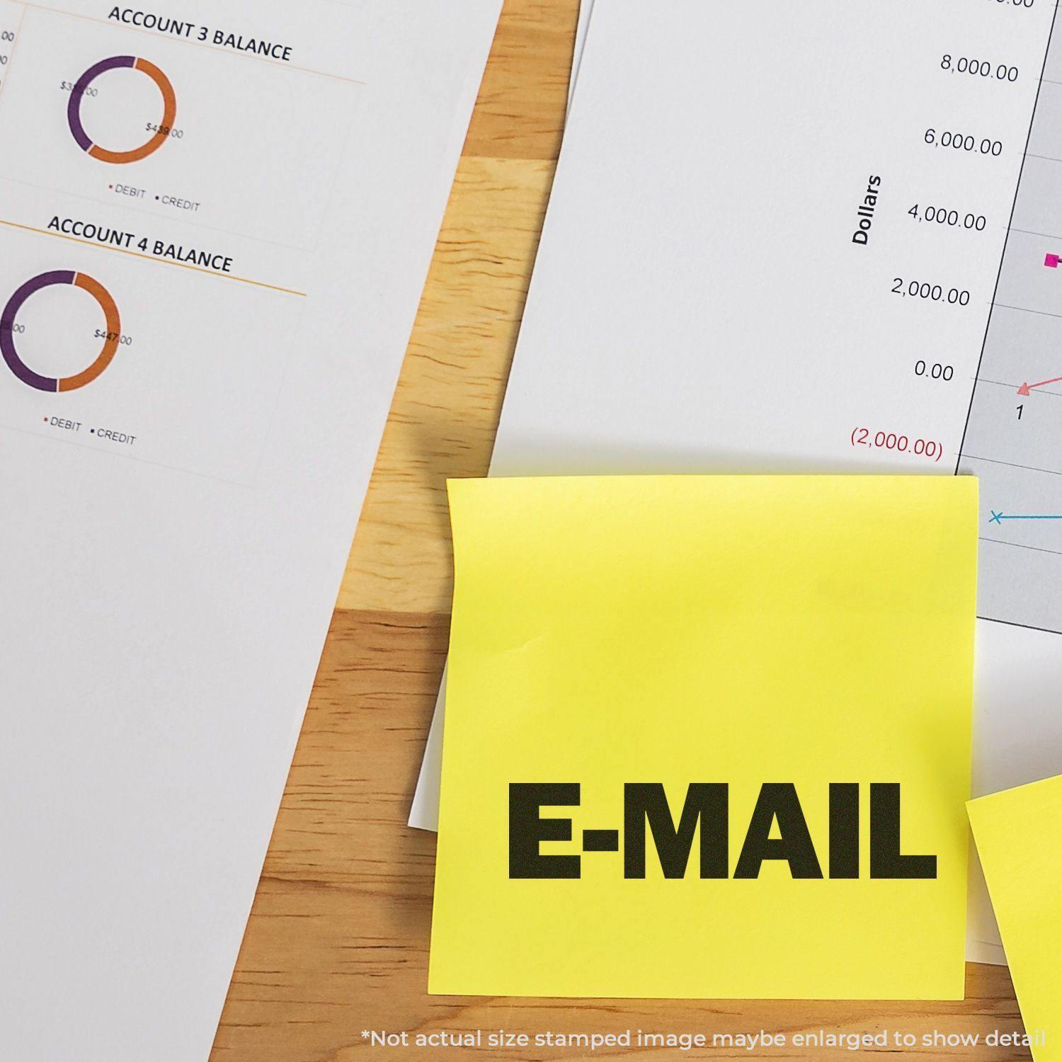 Large Self Inking E-Mail Stamp used on a yellow sticky note, placed on a desk with financial documents and charts in the background.