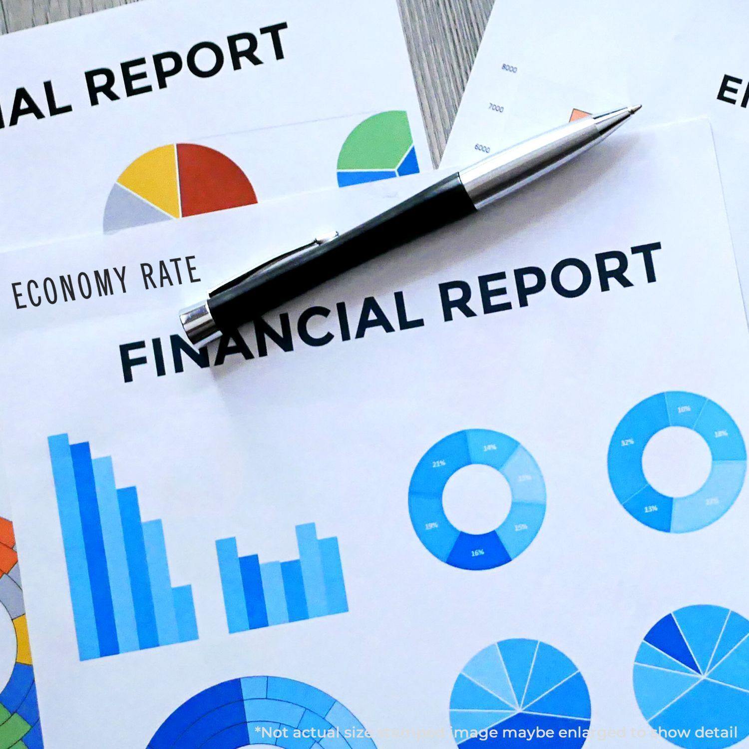 A Large Economy Rate Rubber Stamp is used on financial reports with charts and graphs, alongside a pen on a wooden desk.