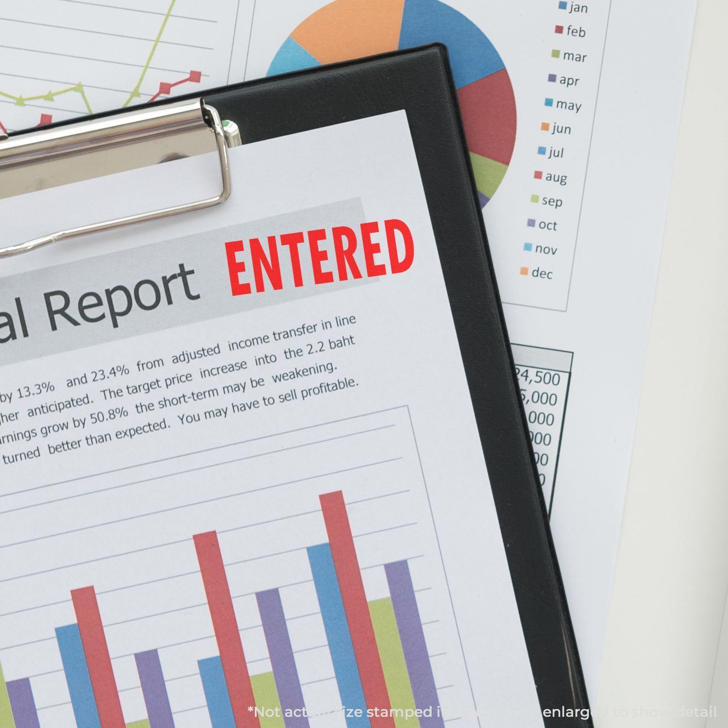 A clipboard holding a financial report stamped with ENTERED using the Self Inking Entered Stamp, with charts and graphs in the background.