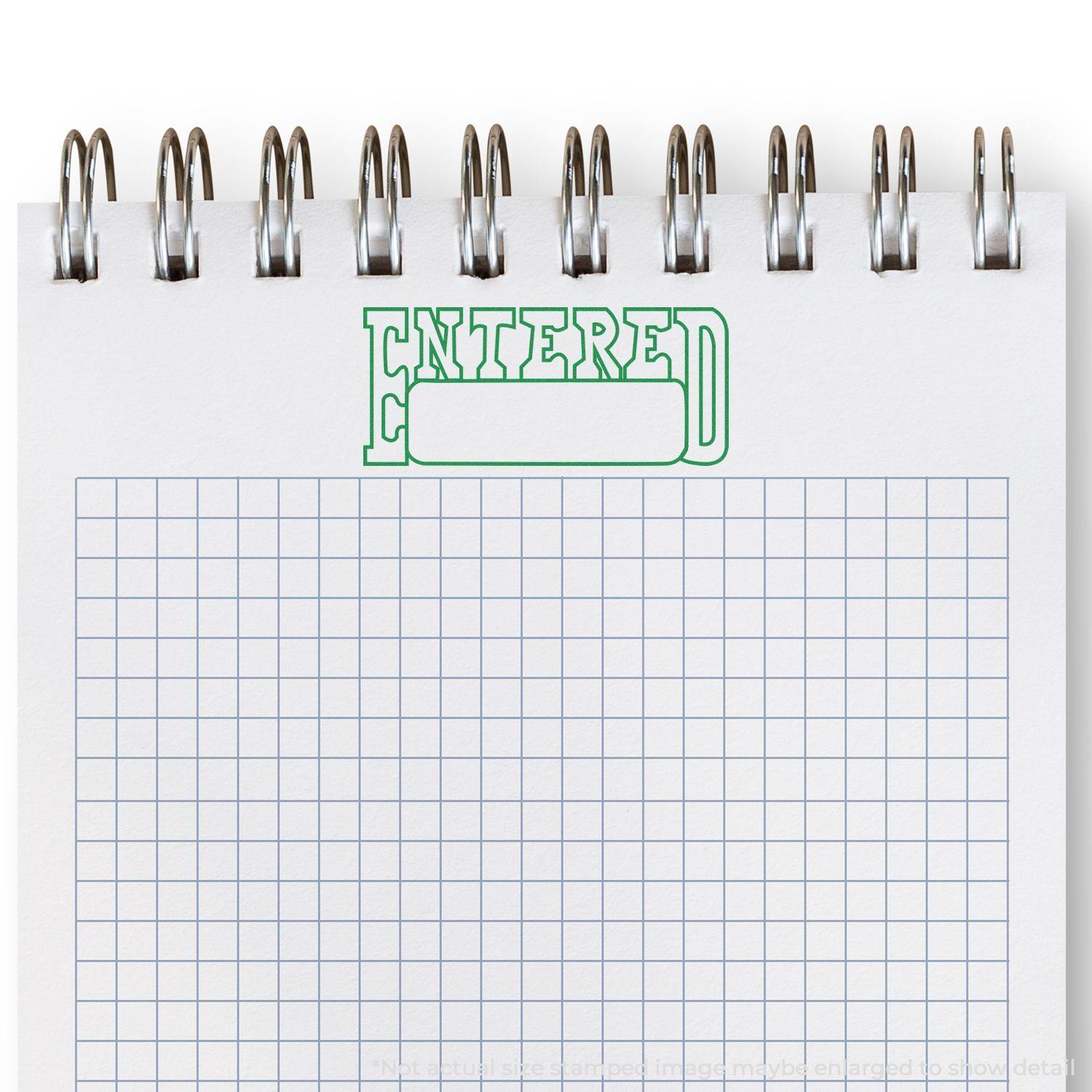 Self Inking Entered with Date Box Stamp in green ink on a spiral-bound notebook with grid paper.