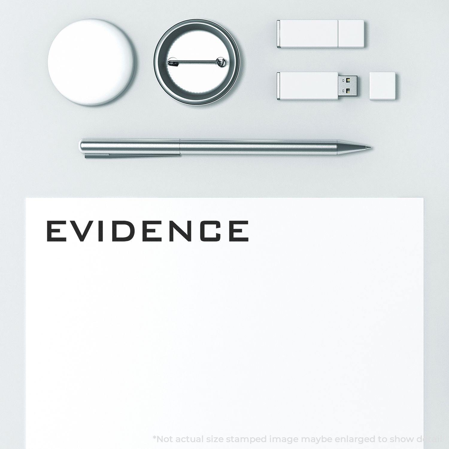 Large Evidence Rubber Stamp used on a white paper, surrounded by a pen, USB drives, and a round badge on a light grey surface.