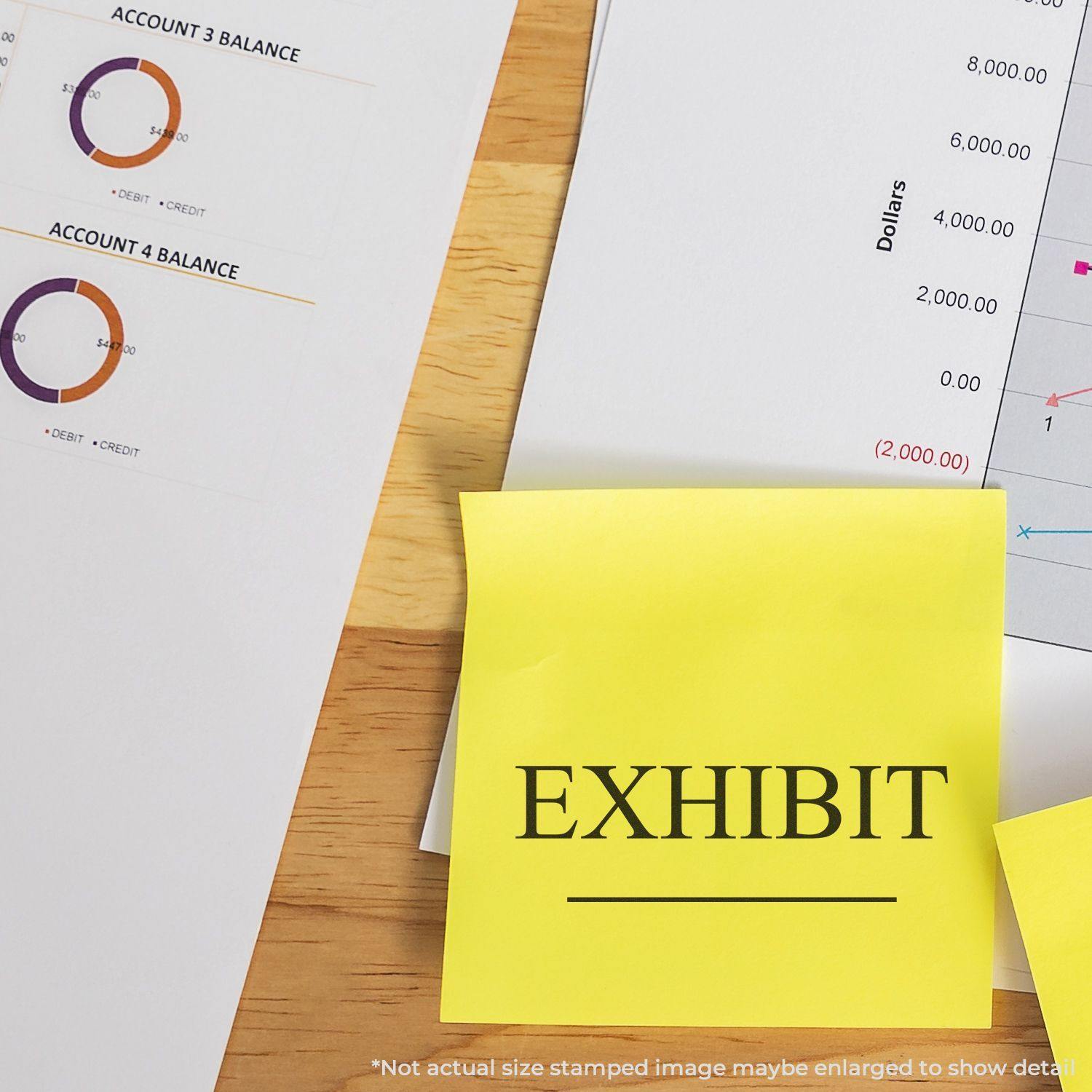 Large Self Inking Exhibit Stamp used on a yellow sticky note placed on financial documents with charts and graphs in the background.