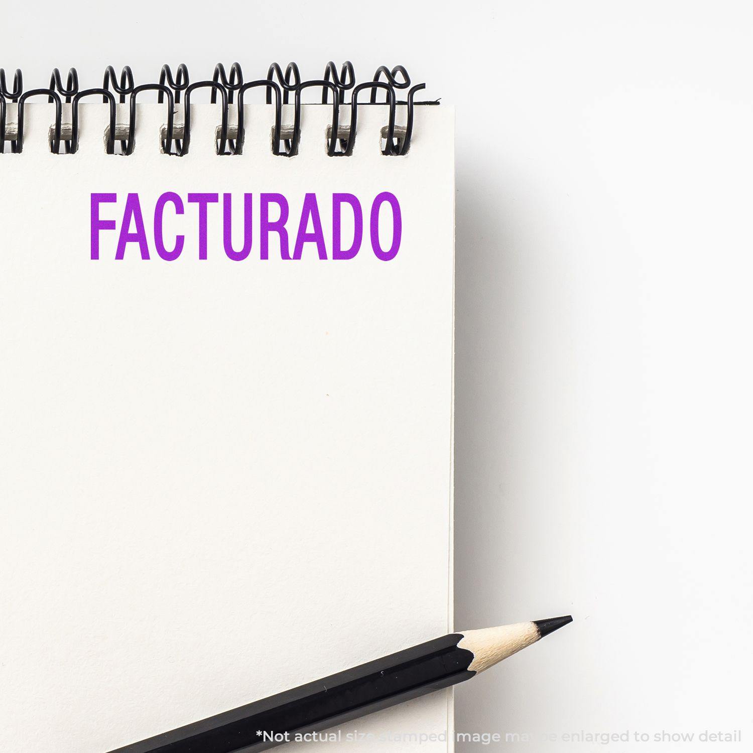 A Facturado Rubber Stamp imprint in purple ink on a white notepad, with a black pencil placed beside the notepad.