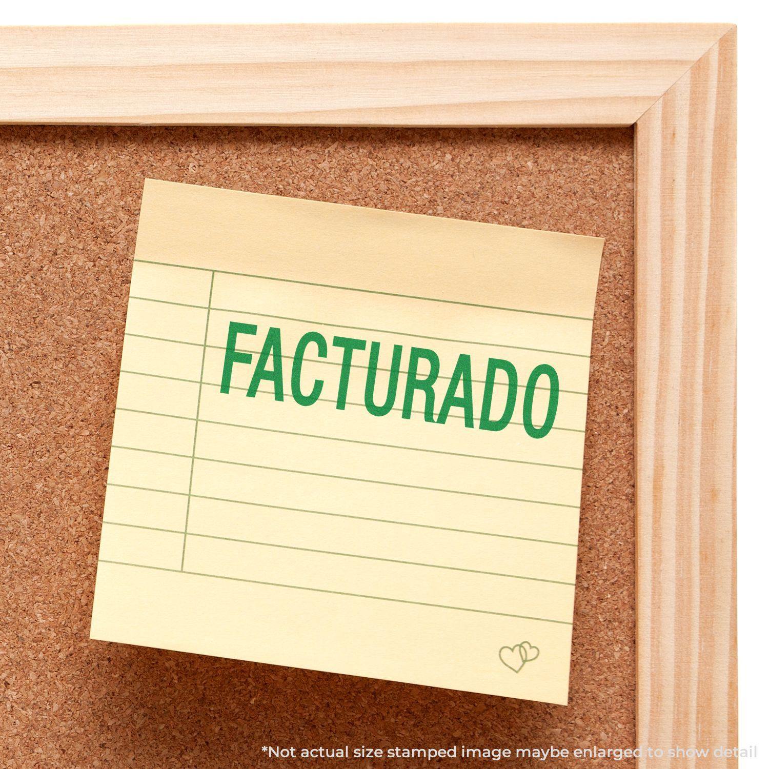 A corkboard with a yellow sticky note stamped with FACTURADO in green ink using the Facturado Rubber Stamp.