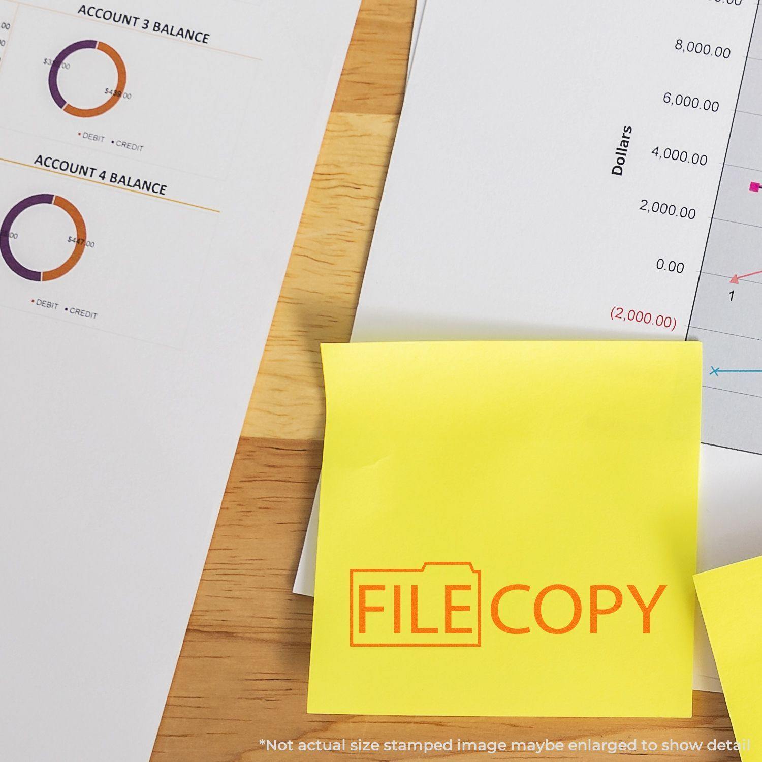 Self Inking File Copy with Folder Stamp used on a yellow sticky note, placed on a desk with financial documents and charts.