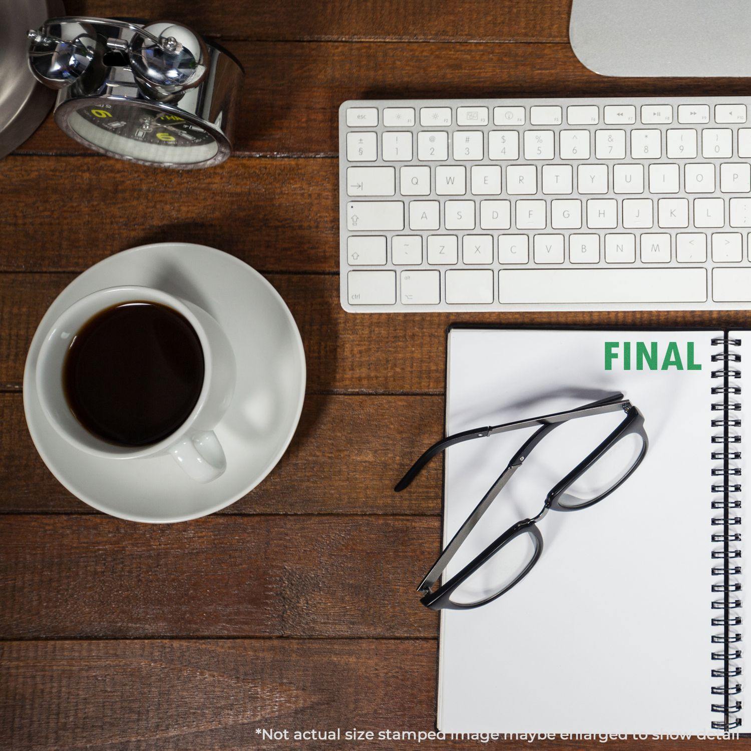 A desk with a keyboard, coffee, glasses, and a notebook stamped with FINAL using the Final Rubber Stamp.