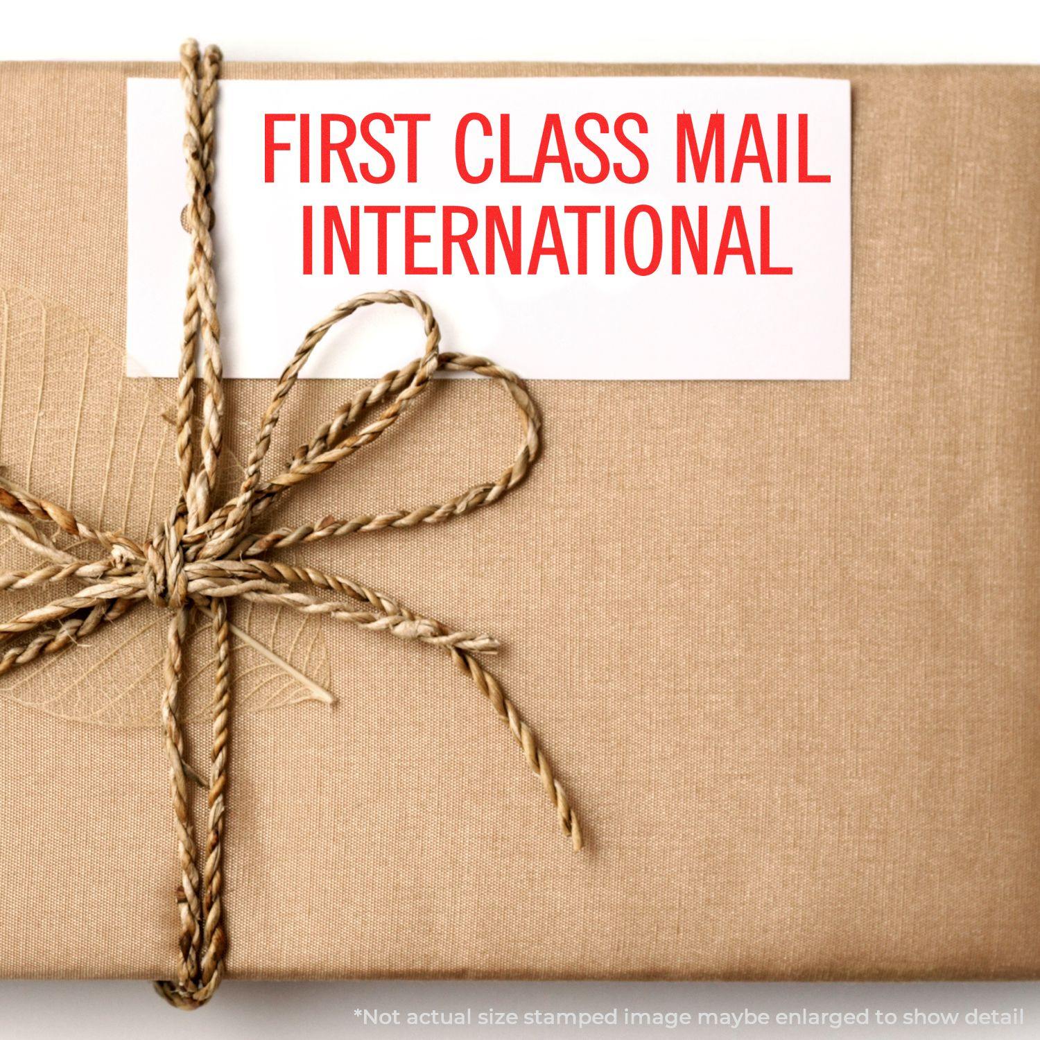 A brown package tied with twine, stamped with First Class Mail International using the Large Self Inking First Class Mail International Stamp.