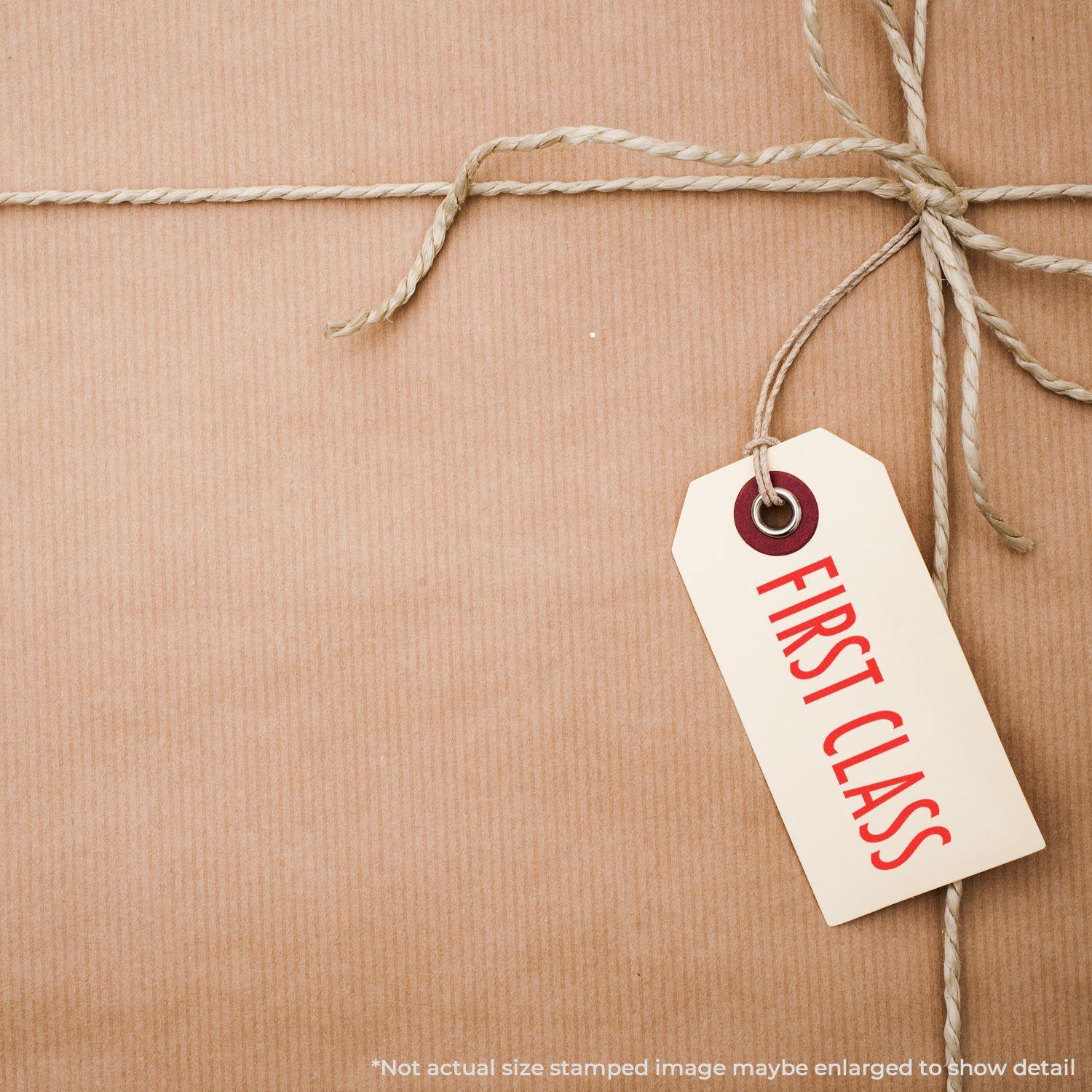 A brown package tied with twine, featuring a tag labeled FIRST CLASS stamped with a Slim Pre-Inked First Class Stamp.