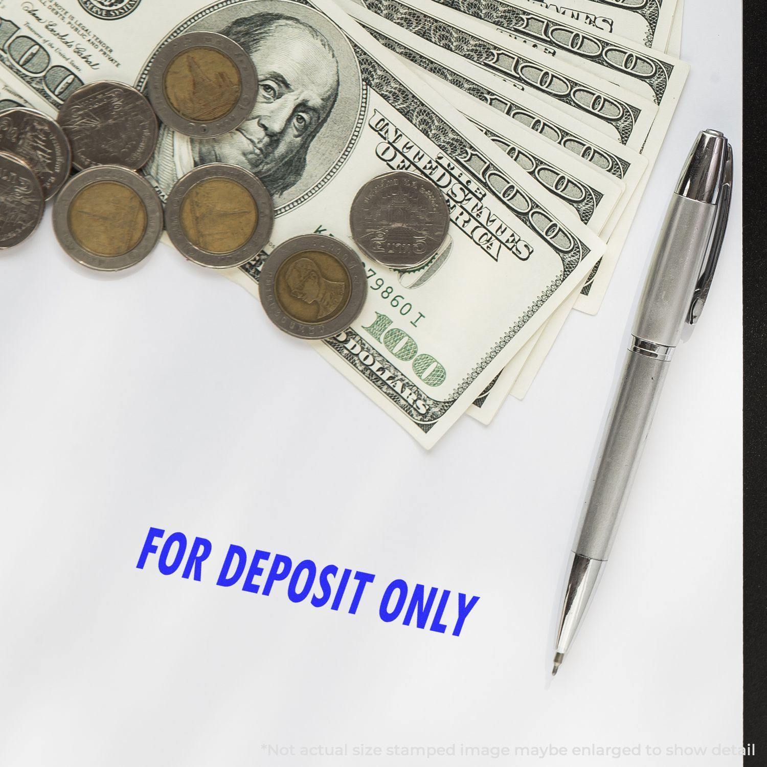 Large Self Inking For Deposit Only Stamp used on paper, surrounded by a pen, US dollar bills, and coins.