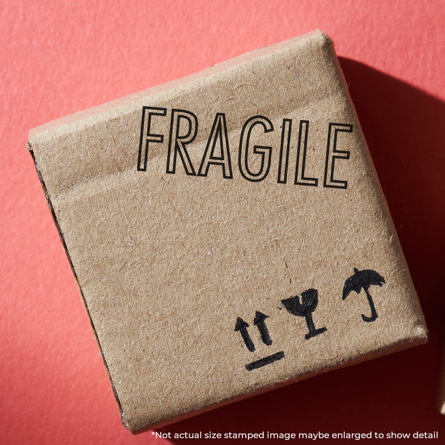 A cardboard box stamped with the Fragile Rubber Stamp, featuring the word FRAGILE and handling symbols, on a red background.