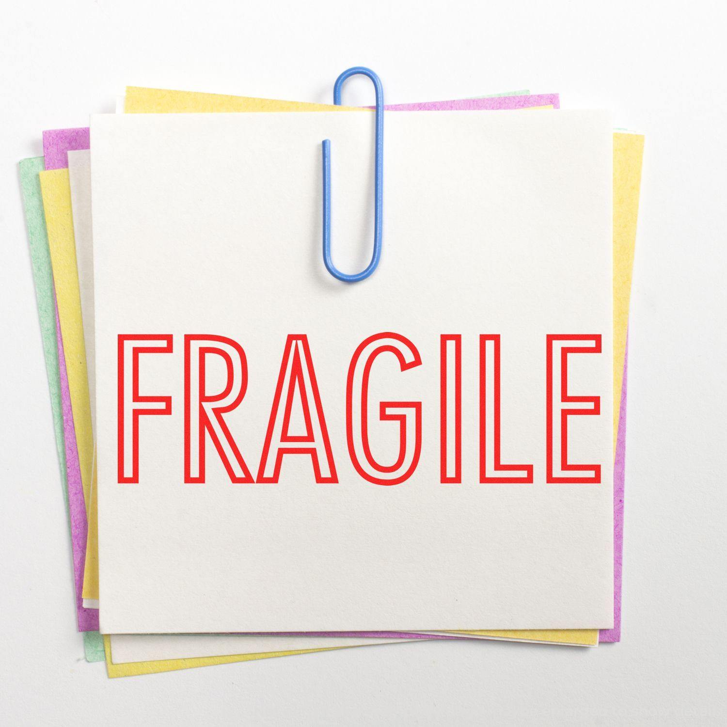 A stack of colorful sticky notes with a blue paperclip, featuring a Fragile stamp in red. Product name: Fragile Rubber Stamp.