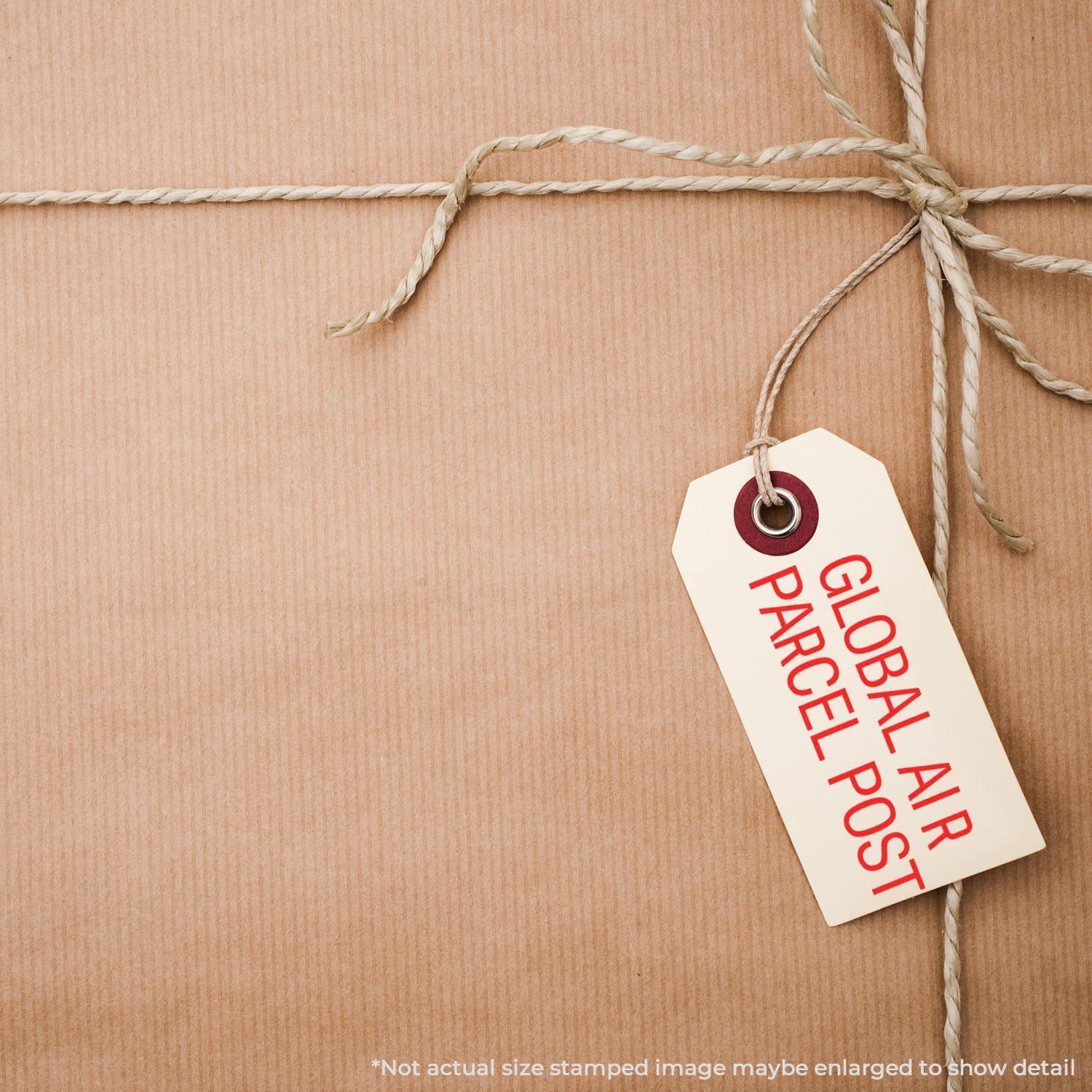 A brown parcel tied with twine and a tag stamped with Global Air Parcel Post Rubber Stamp in red ink.