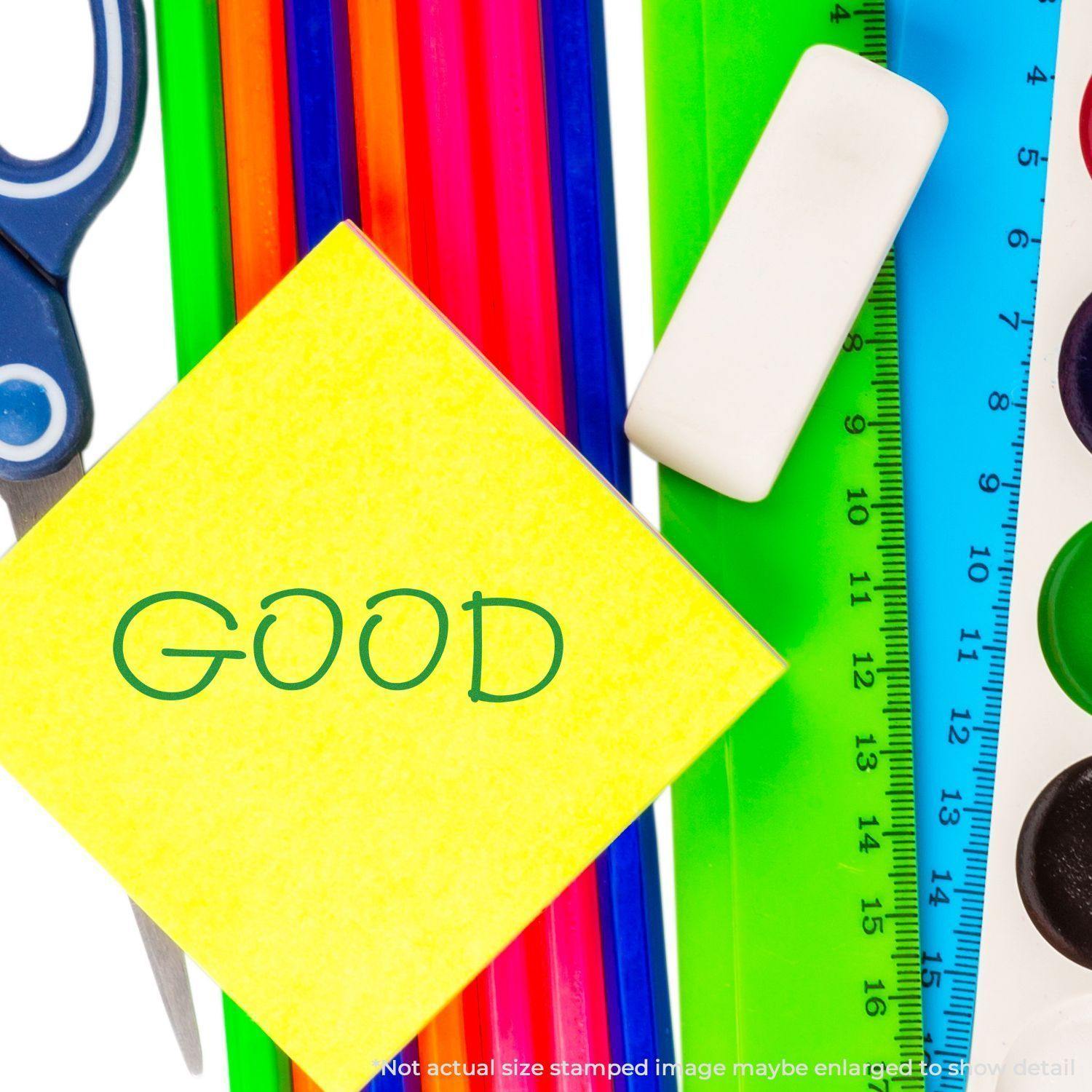 Large Pre-Inked Good Stamp used on a yellow sticky note, surrounded by colorful stationery items like scissors, ruler, and eraser.