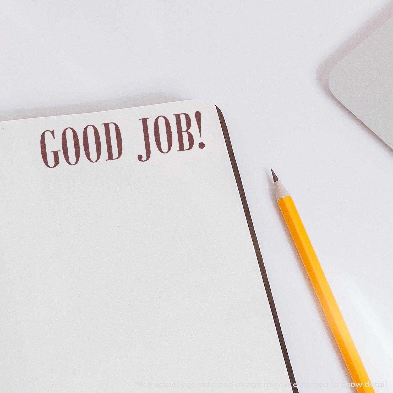 Notebook with 'GOOD JOB!' stamped on the page using the Large Good Job Rubber Stamp, next to a yellow pencil on a white desk.