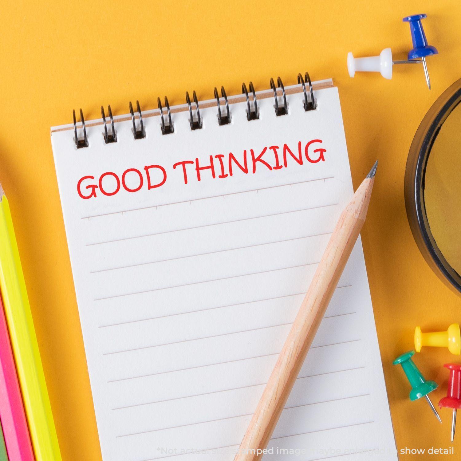 A Large Good Thinking Rubber Stamp is used on a spiral notebook with a pencil, colorful pens, and push pins on a yellow background.