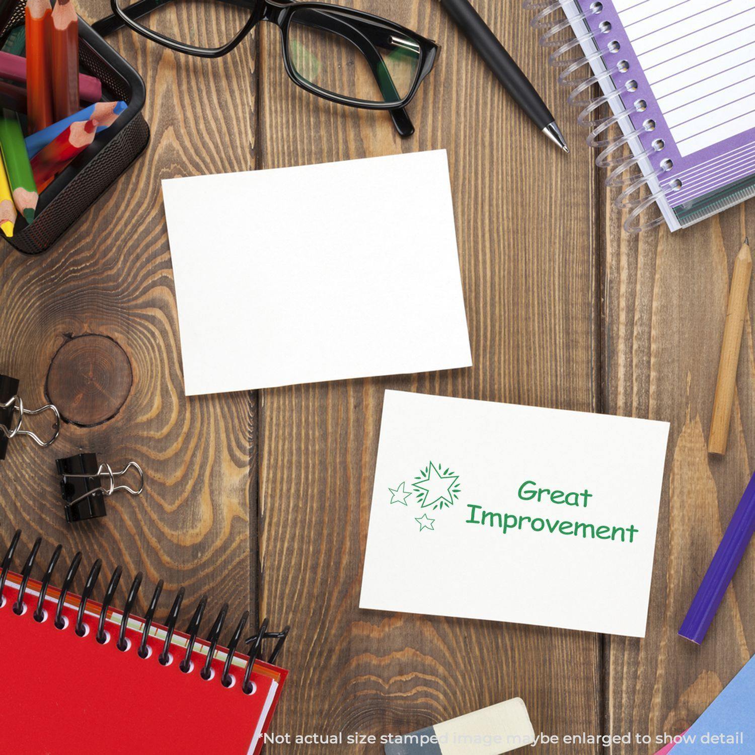 A desk with stationery, glasses, and a card stamped with Great Improvement Rubber Stamp in green ink.