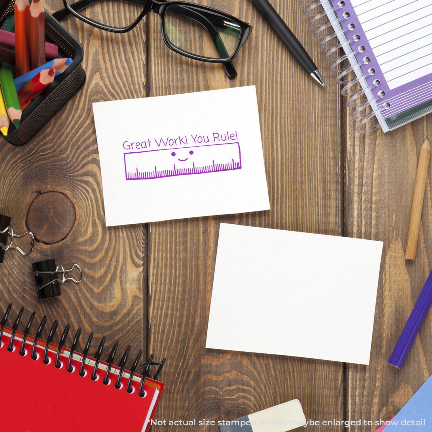 A desk with stationery, glasses, and a card stamped with Great Work! You Rule! using the Great Work You Rule Rubber Stamp.