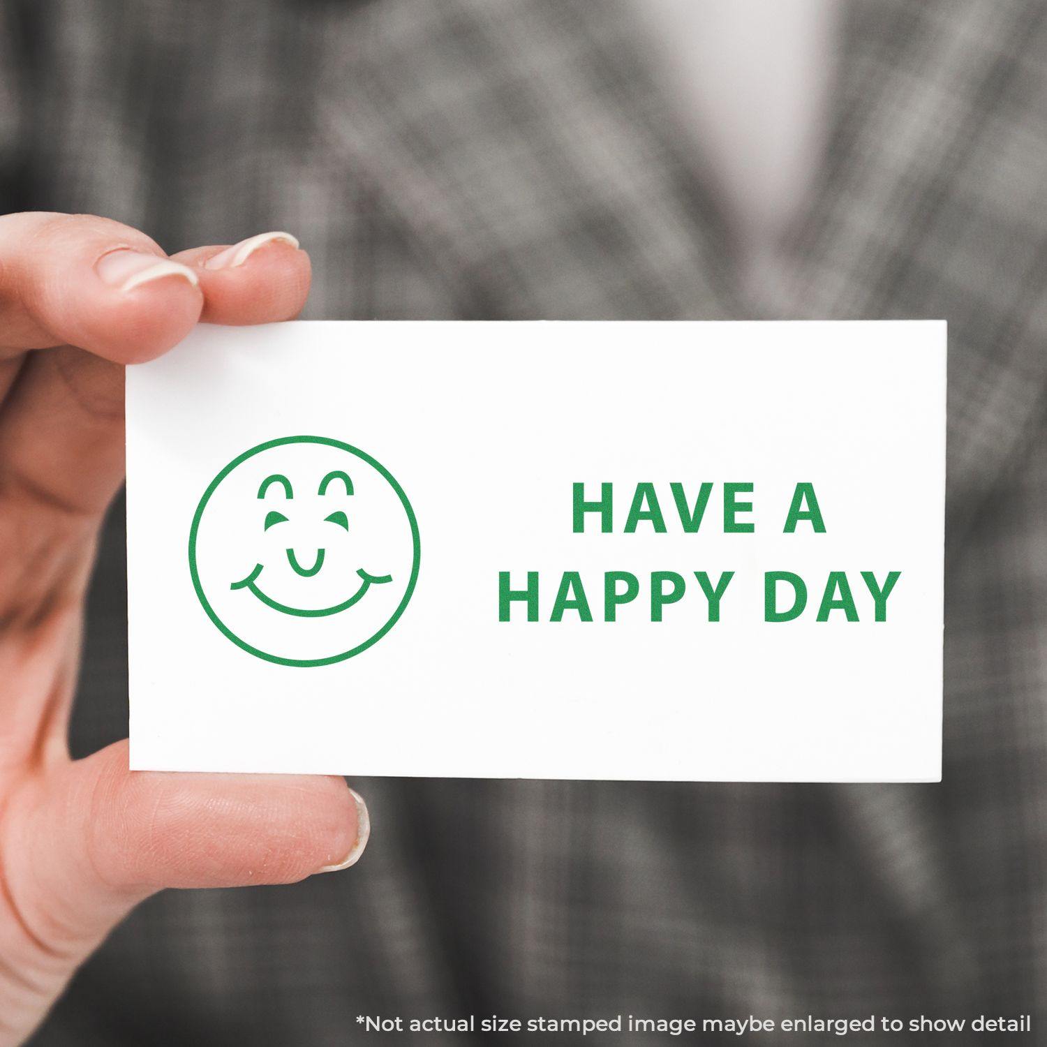 A hand holding a card stamped with a green smiley face and the text HAVE A HAPPY DAY using the Have a Happy Day Rubber Stamp.