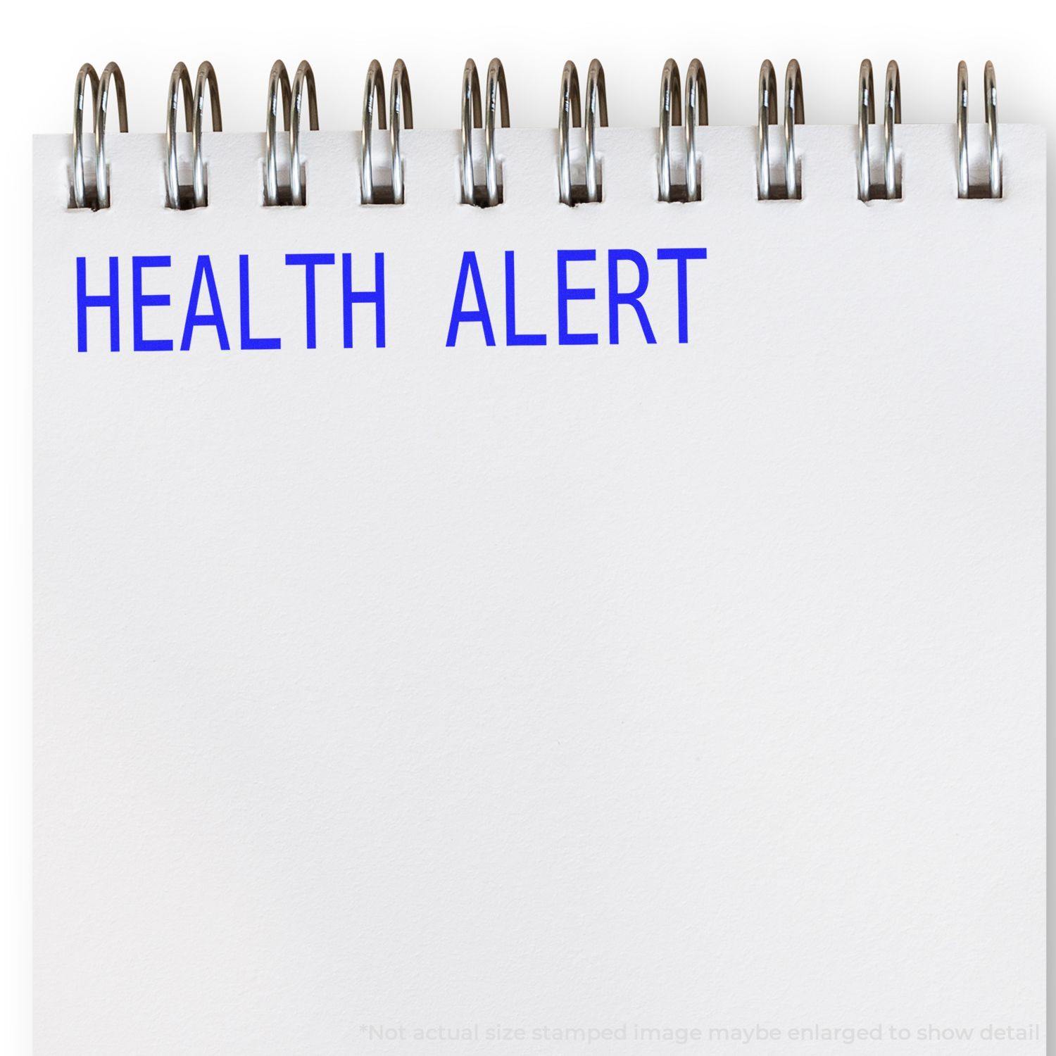 Large Pre-Inked Health Alert Stamp in blue ink on a white notepad with spiral binding, displaying the text HEALTH ALERT .