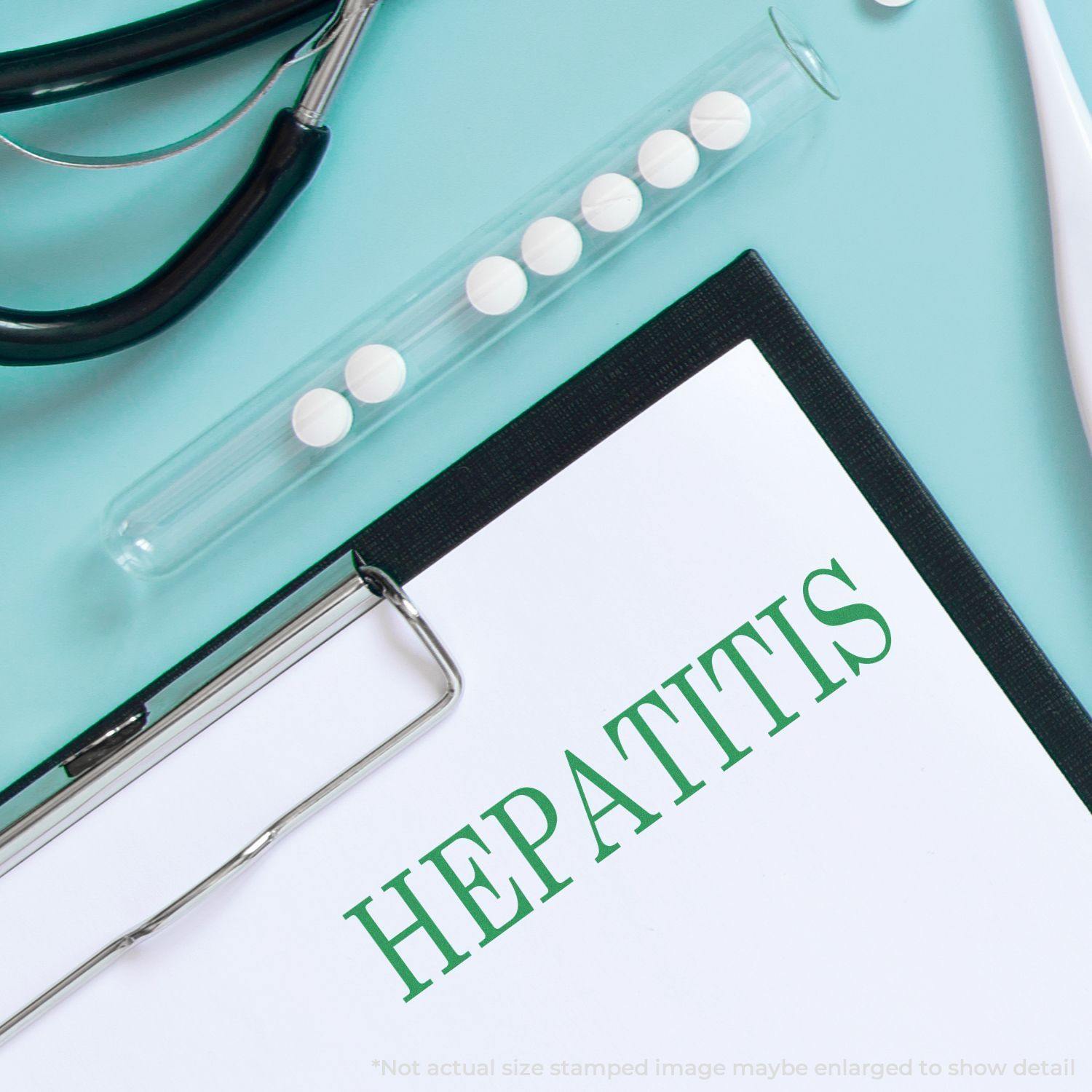 Large Self Inking Hepatitis Stamp marking HEPATITIS on paper, with a stethoscope and pills in the background.