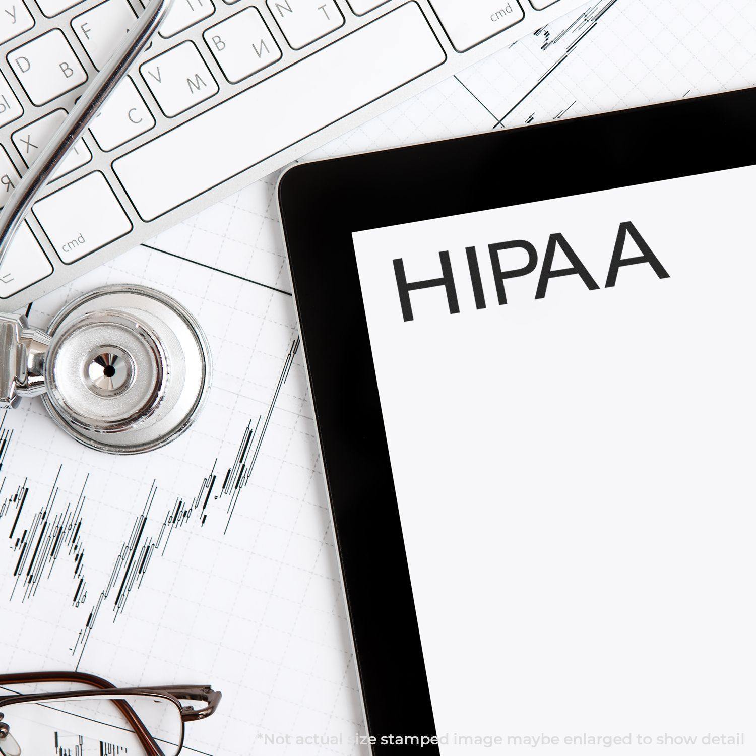 A Hipaa Medical Rubber Stamp is shown on a desk with a stethoscope, keyboard, and tablet displaying the word HIPAA .