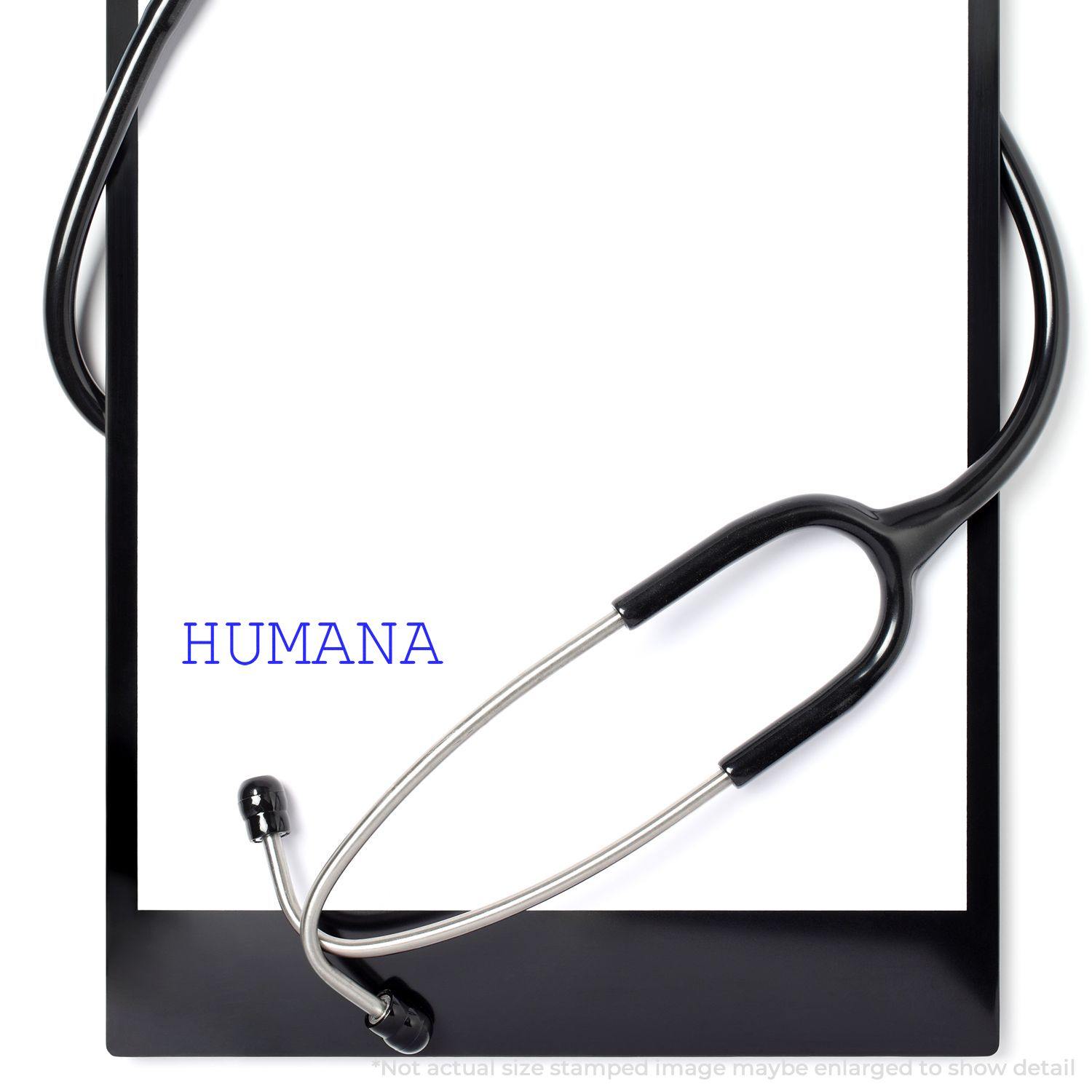 Humana Rubber Stamp imprint on a white paper with a stethoscope draped over a black clipboard.