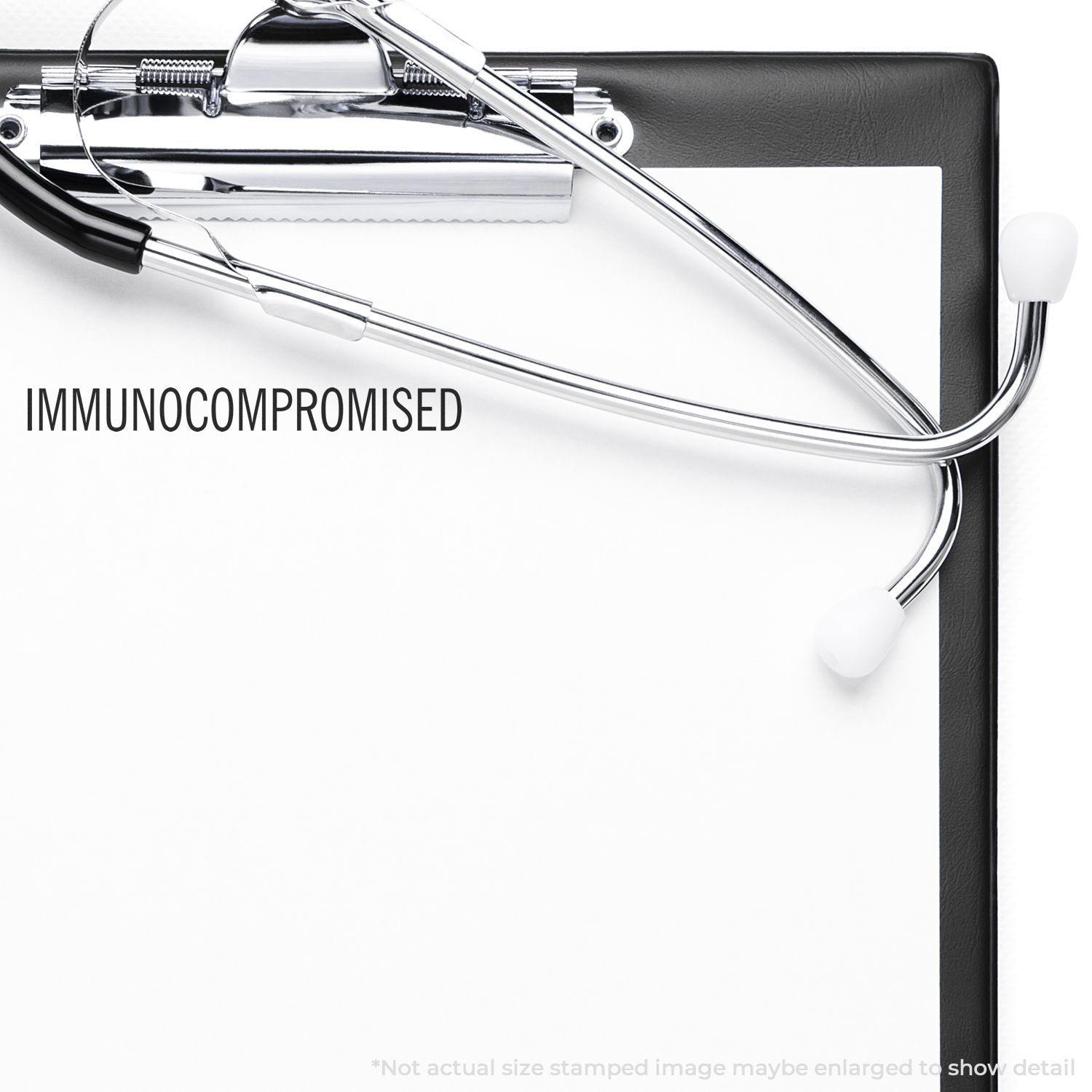 Large Pre-Inked Immunocompromised Stamp used on a clipboard with a stethoscope, showing the word IMMUNOCOMPROMISED clearly stamped.