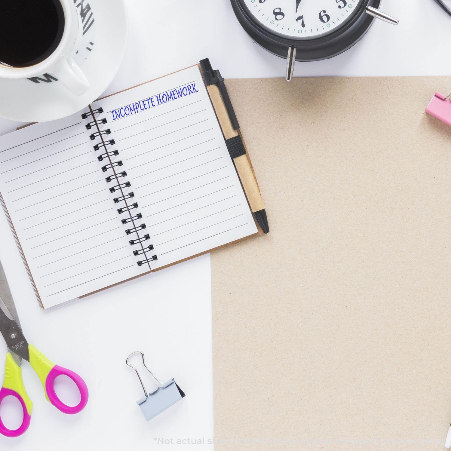 A desk with a notebook stamped Incomplete Homework using the Incomplete Homework Rubber Stamp, surrounded by a clock, coffee cup, scissors, and paper.