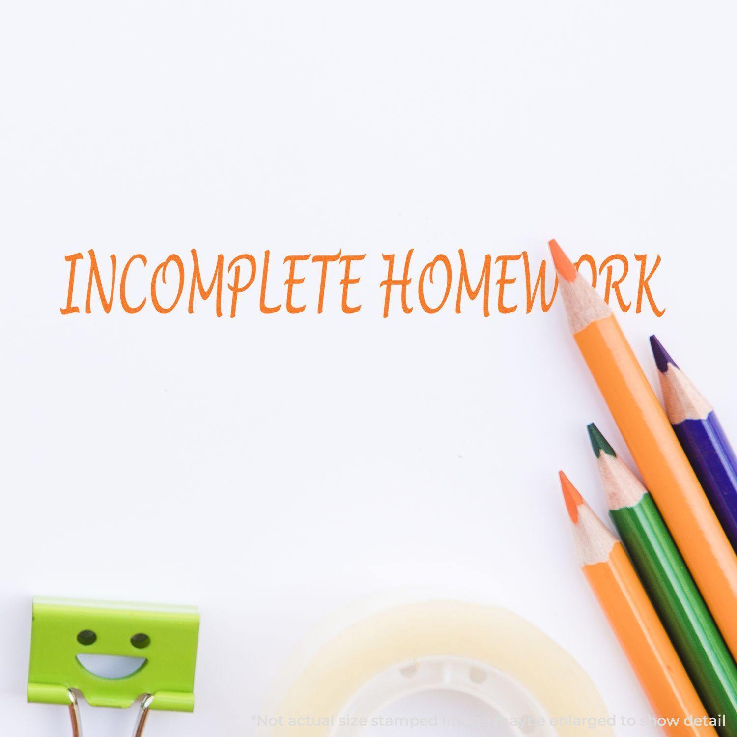 Incomplete Homework Rubber Stamp impression in orange ink on paper, surrounded by colorful pencils, a smiling paper clip, and tape.