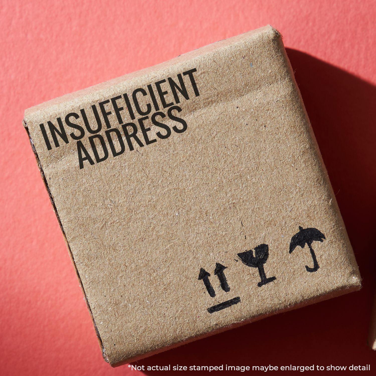 A cardboard box stamped with INSUFFICIENT ADDRESS using a Slim Pre-Inked Insufficient Address Stamp against a red background.