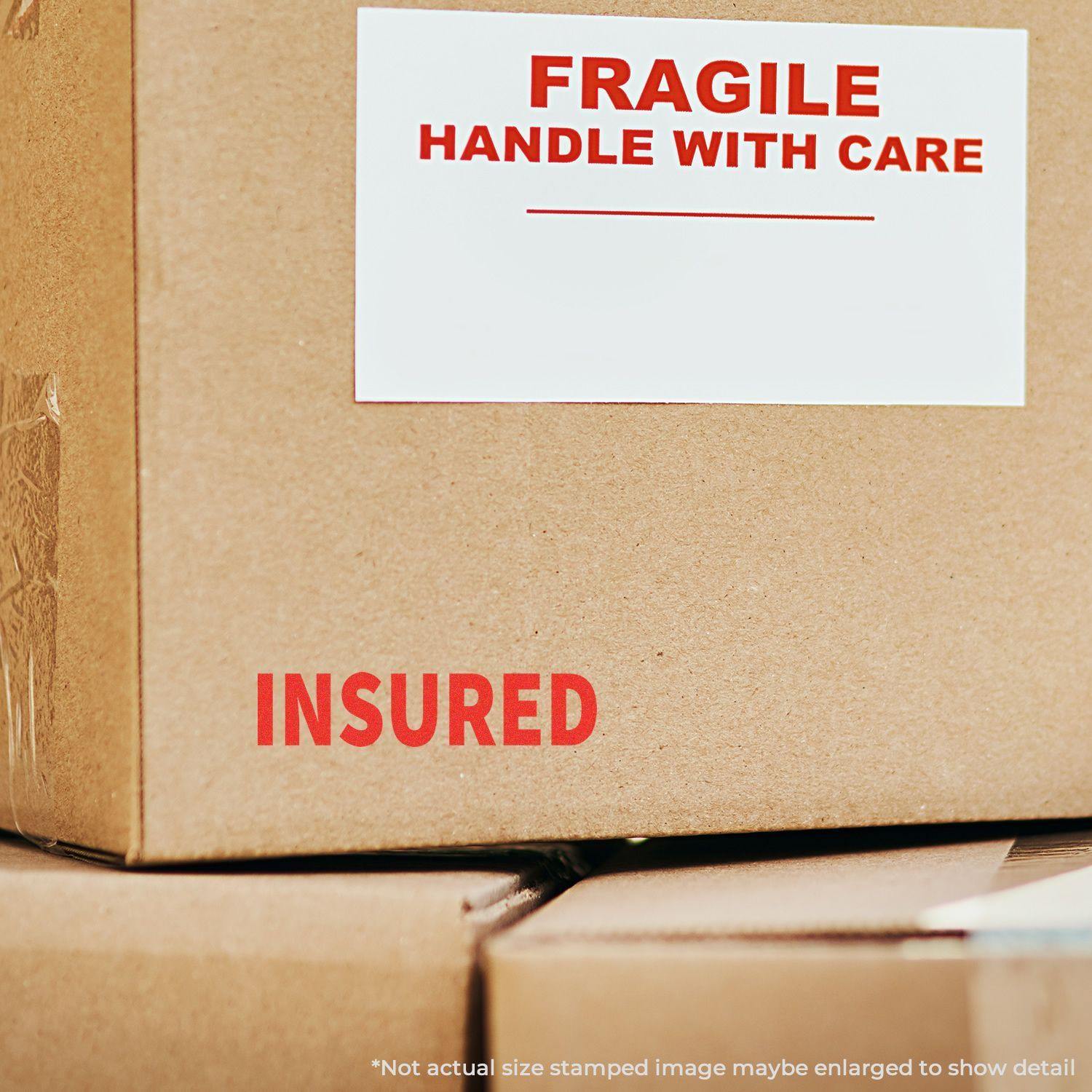 Cardboard box with FRAGILE HANDLE WITH CARE label and INSURED stamped in red using the Large Pre-Inked Insured Stamp.