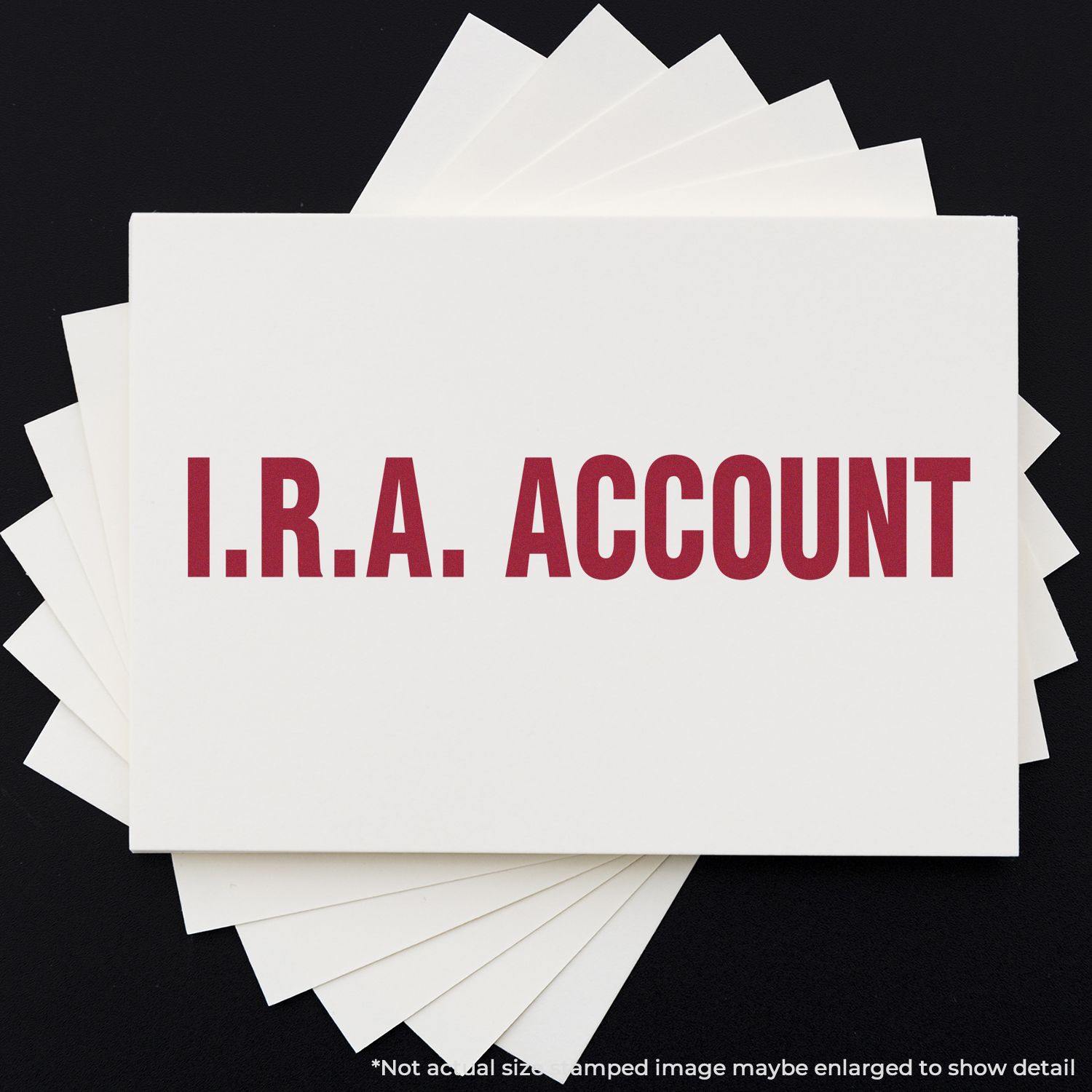 Large Pre-Inked I.R.A. Account Stamp in red ink on white paper, with multiple sheets stacked underneath on a black background.