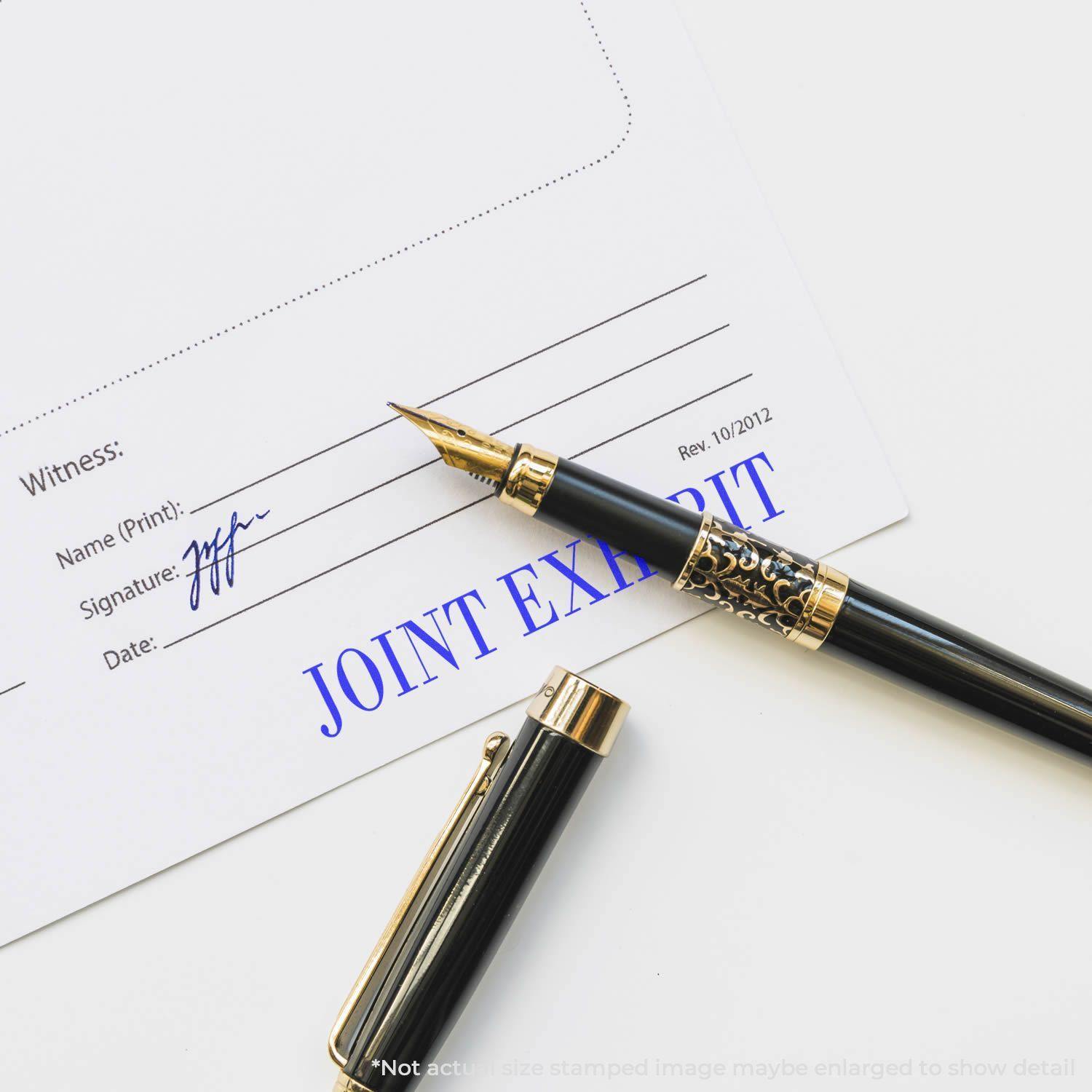 A Large Pre-Inked Joint Exhibit Stamp marks a document with JOINT EXHIBIT in blue ink, next to a black and gold fountain pen.