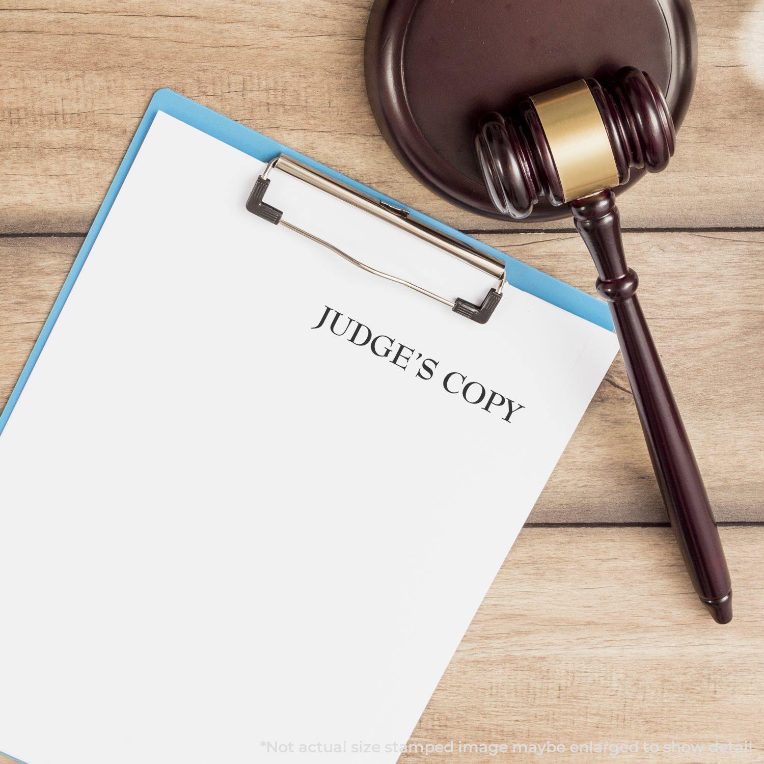 A clipboard with a paper stamped JUDGE'S COPY using the Large Self Inking Judges Copy Stamp, next to a gavel on a wooden surface.