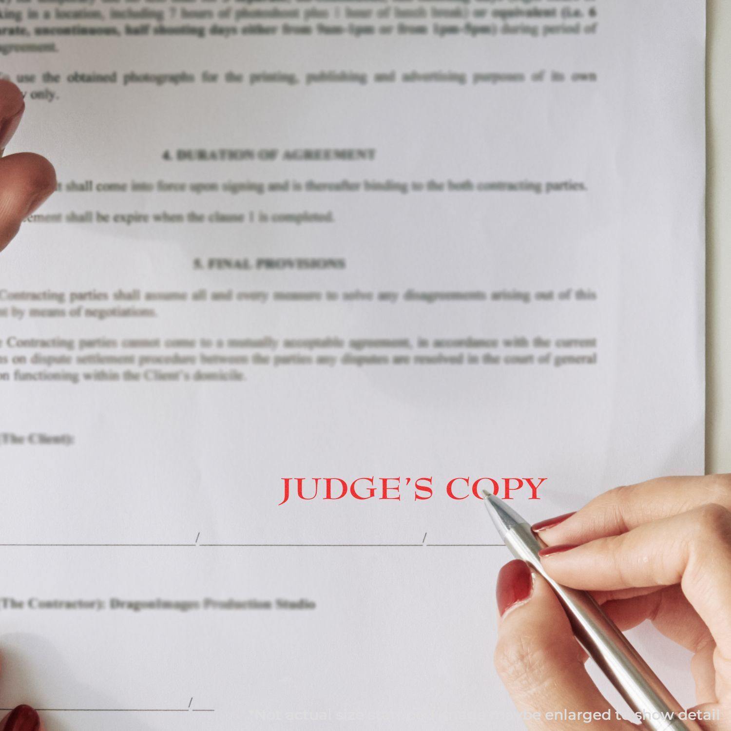 A hand using the Large Pre-Inked Judge's Copy Stamp on a legal document, leaving a clear red JUDGE'S COPY mark on the paper.