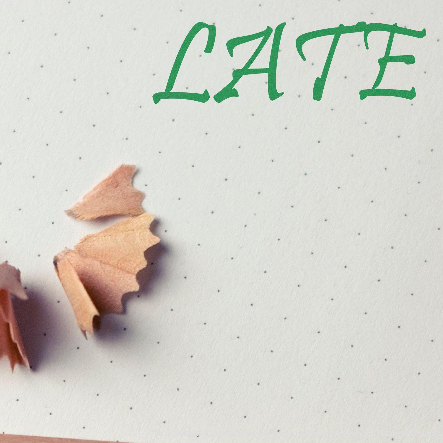 Large Self Inking Late Stamp marking "LATE" in green ink on dotted paper, with pencil shavings nearby.