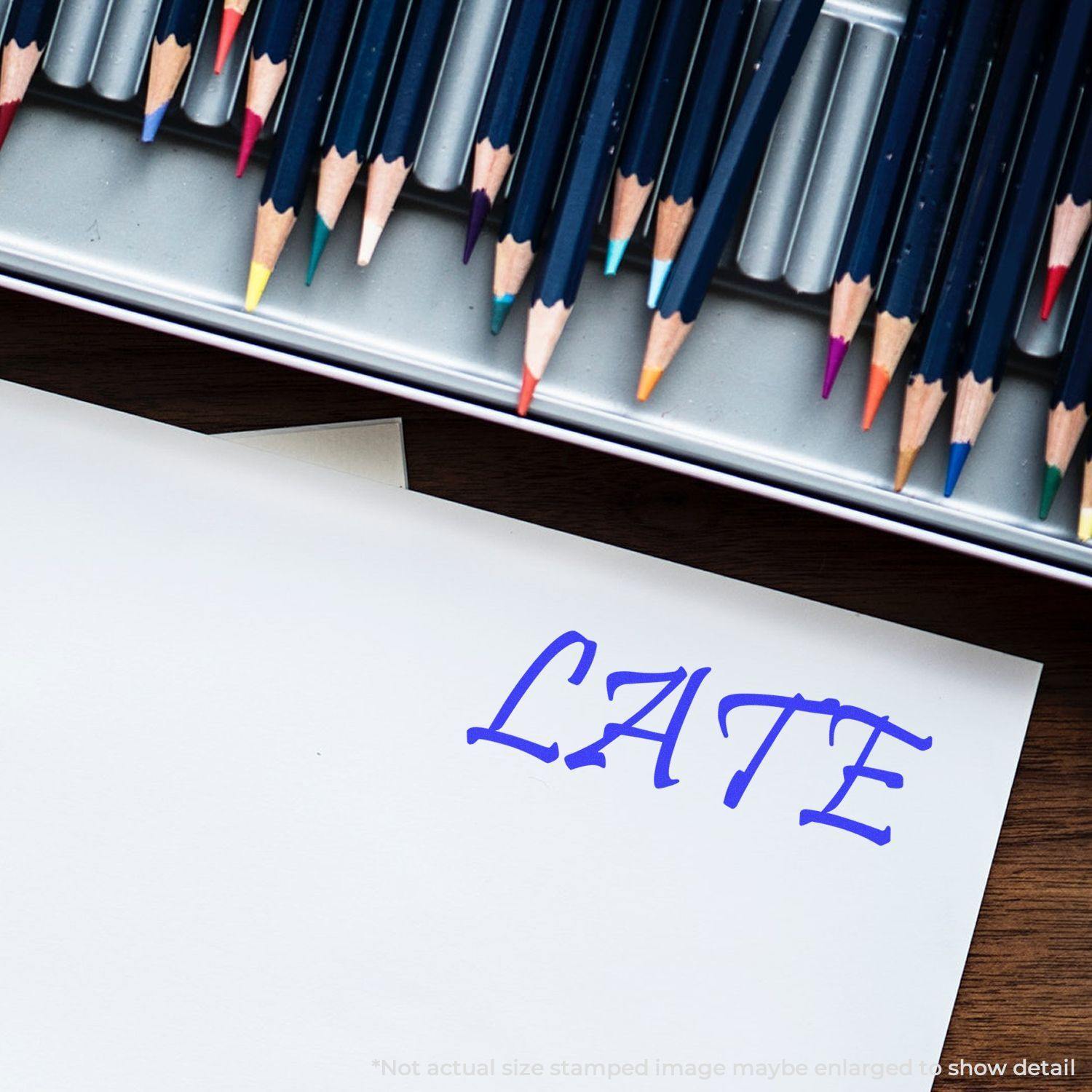 A Large Pre-Inked Late Stamp marks a white paper with LATE in blue ink, surrounded by colored pencils in a metal case.