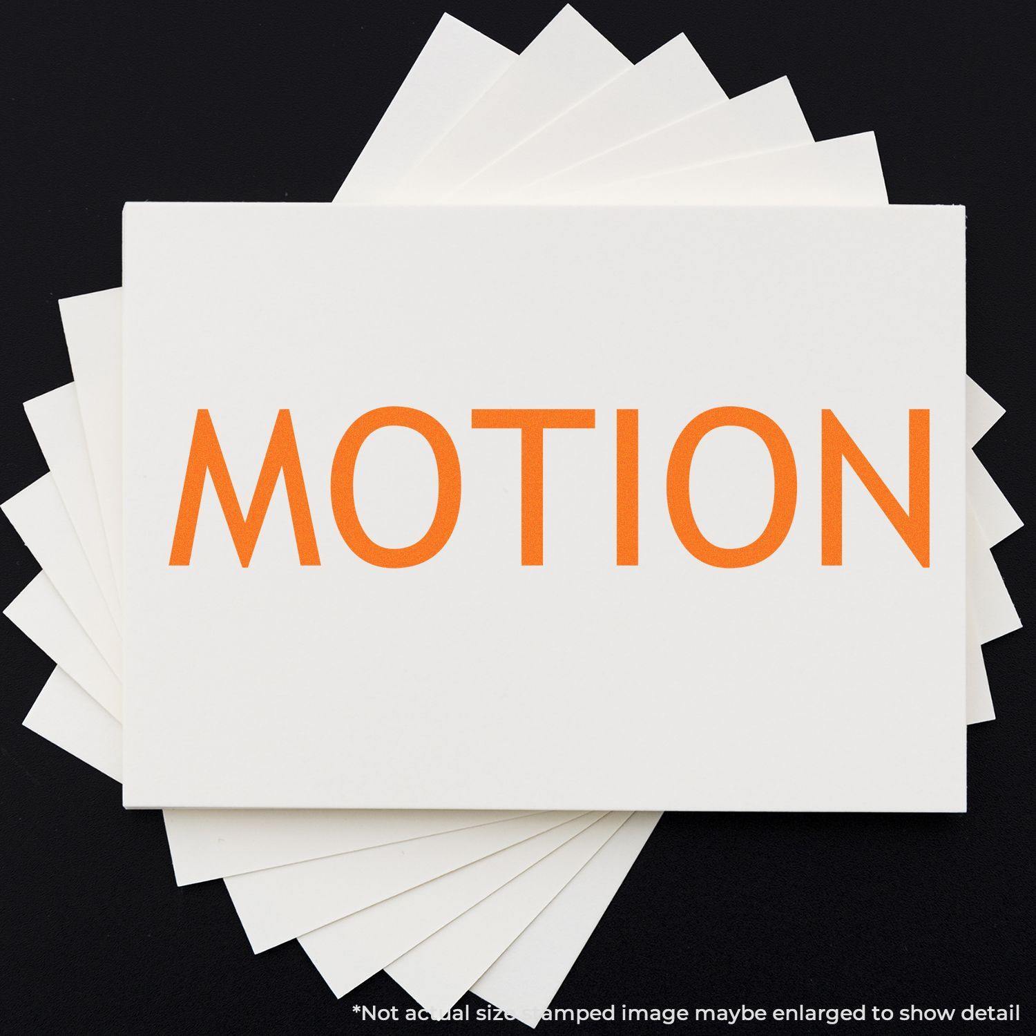 Large Motion Rubber Stamp in use, displaying the word MOTION in bold orange letters on a white card against a black background.