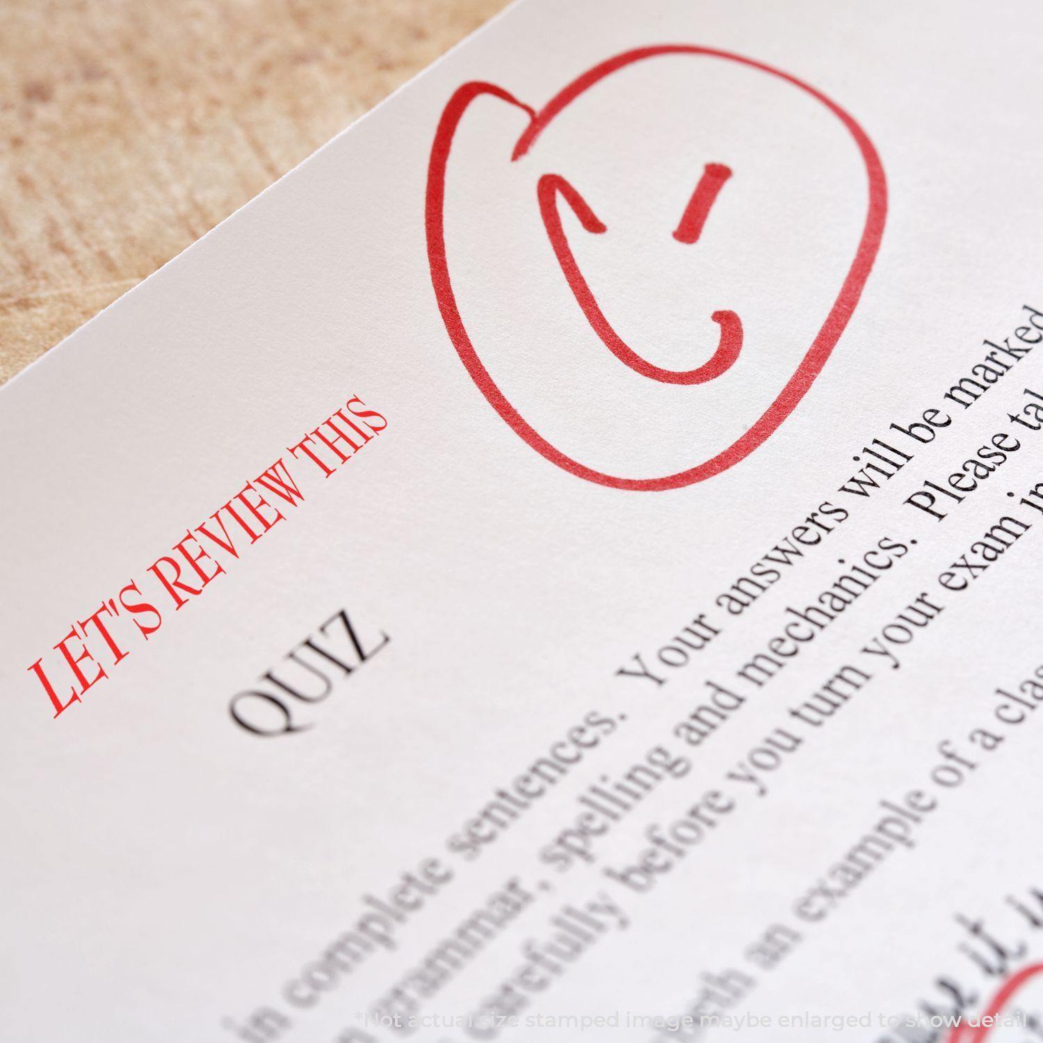 Slim Pre-Inked Let's Review This Stamp in red ink on a quiz paper with a smiley face, highlighting the need for review.