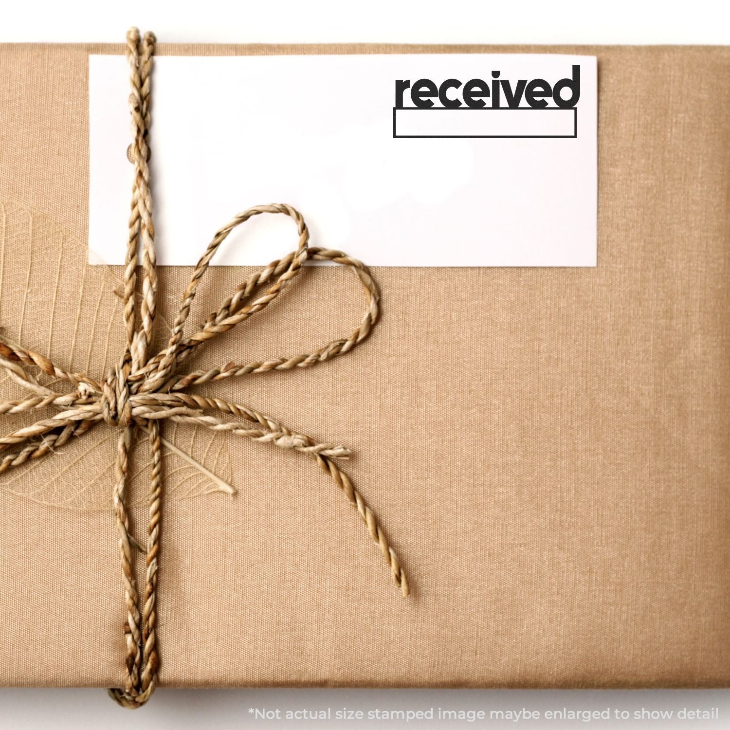 A package wrapped in brown paper with a card stamped received using the Self Inking Lowercase Received with Date Box Stamp.