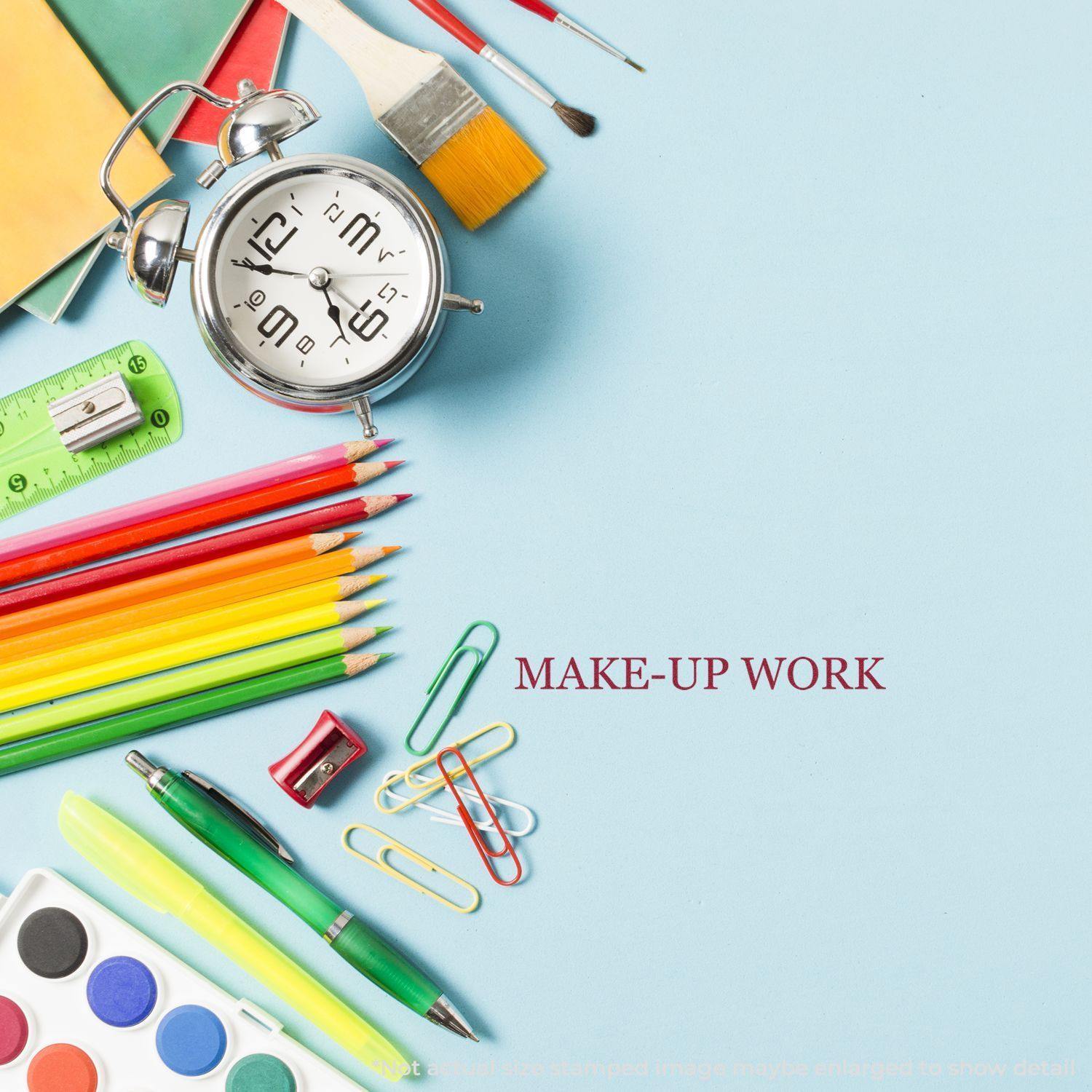 A desk with colorful stationery, an alarm clock, and a Large Make Up Work Rubber Stamp imprint on blue paper.