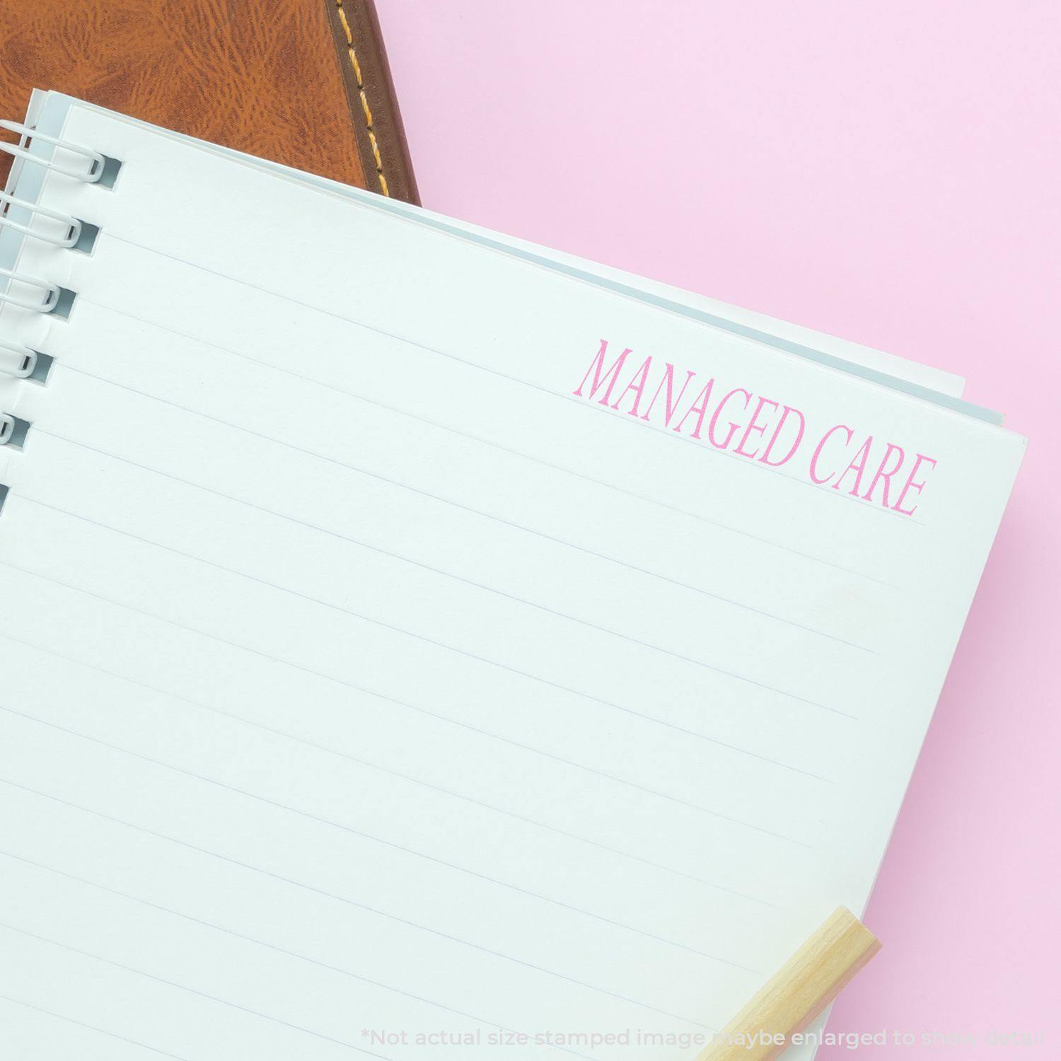 Large Managed Care Rubber Stamp used on a white notebook page with pink MANAGED CARE text, next to a brown leather item on a pink background.