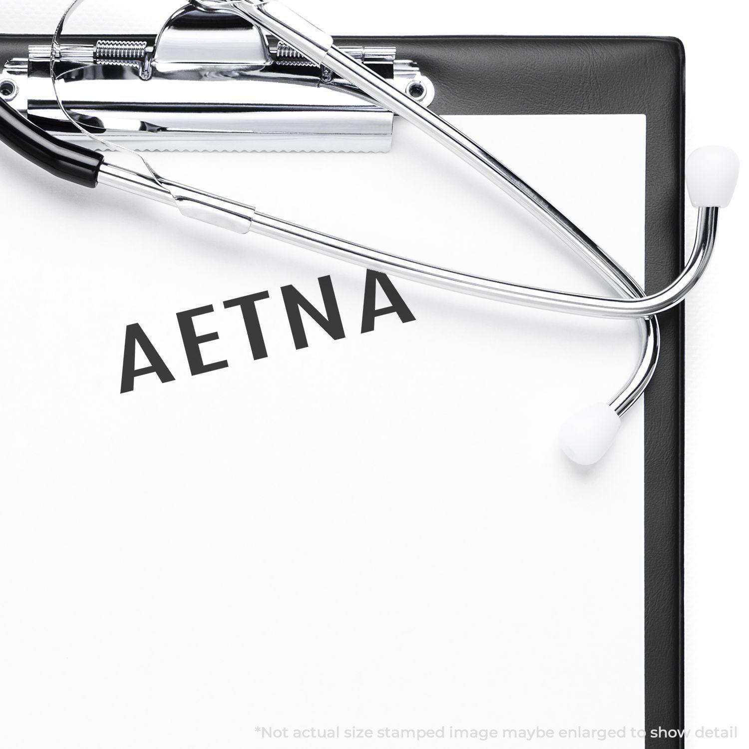 Large Pre-Inked Aetna Stamp used on a clipboard with a stethoscope, showing the word AETNA clearly stamped on the paper.