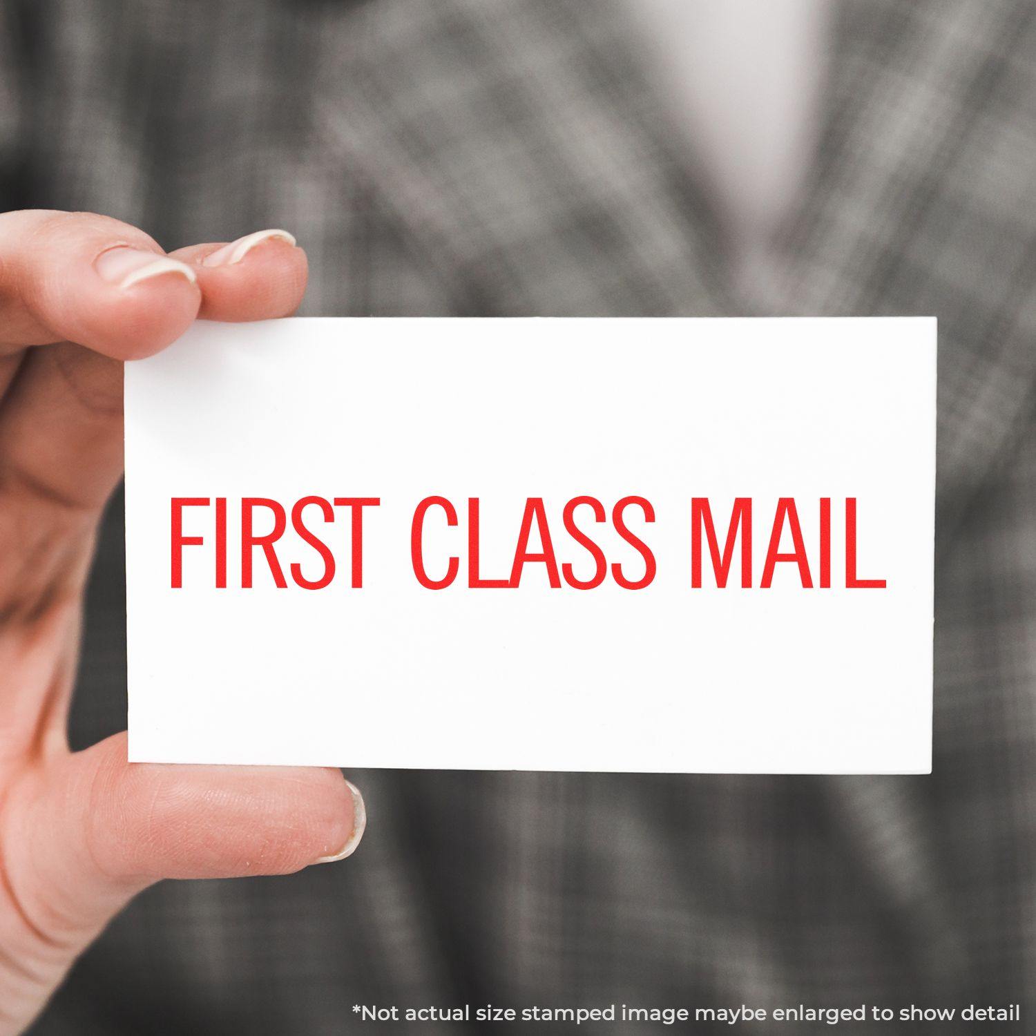 Person holding a card stamped with FIRST CLASS MAIL in red ink using the Large Pre-Inked Narrow First Class Mail Stamp.