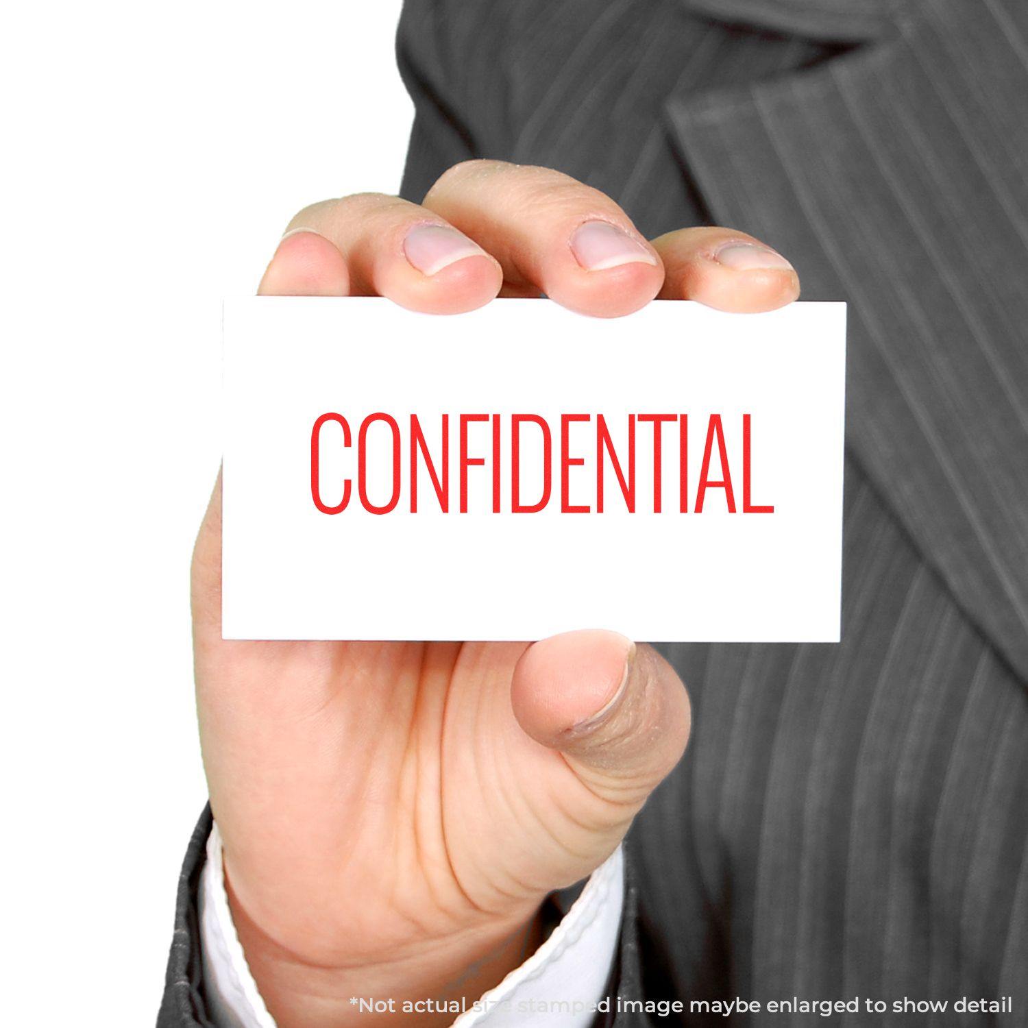 Hand holding a card stamped with CONFIDENTIAL in red using the Large Self Inking Narrow Font Confidential Stamp.