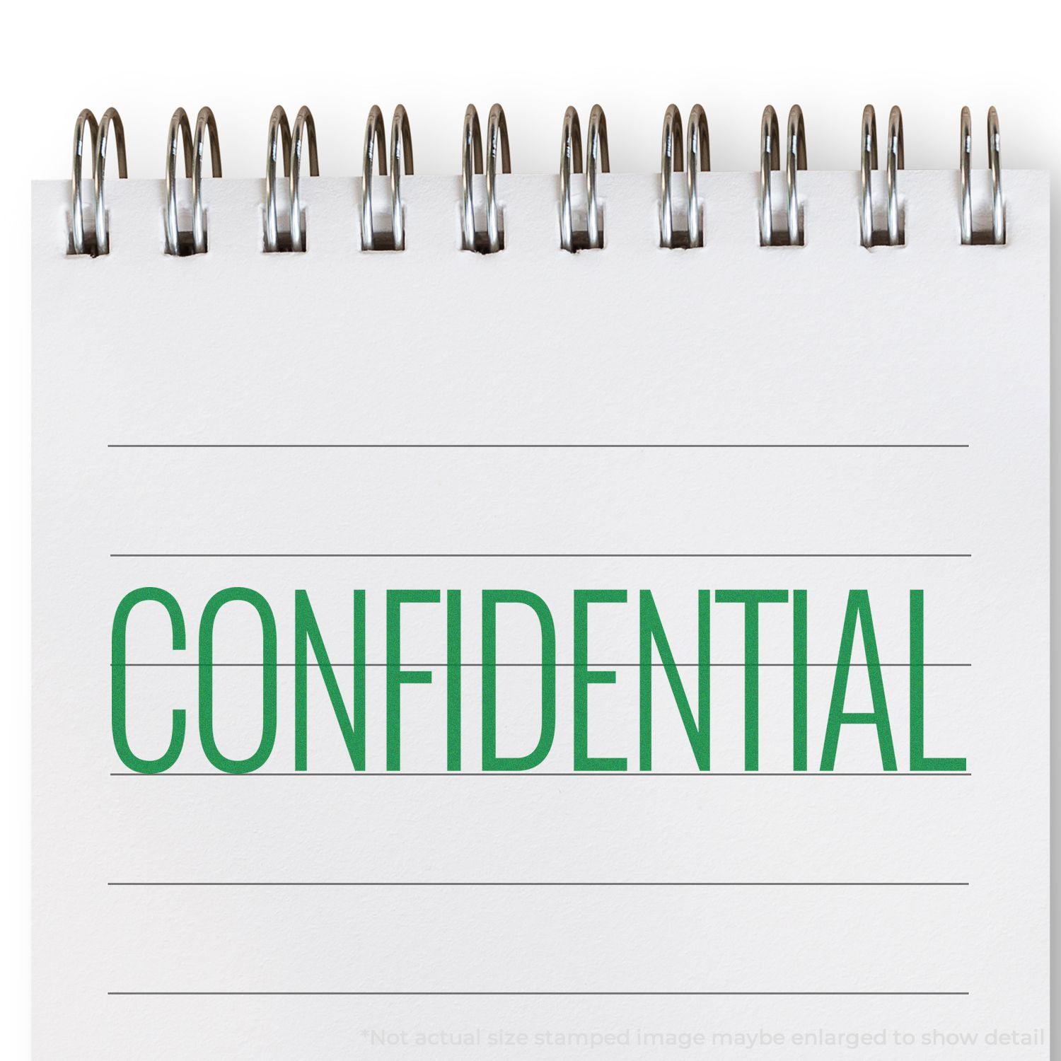 Slim Pre-Inked Narrow Font Confidential Stamp on a spiral notebook with the word CONFIDENTIAL stamped in green ink.