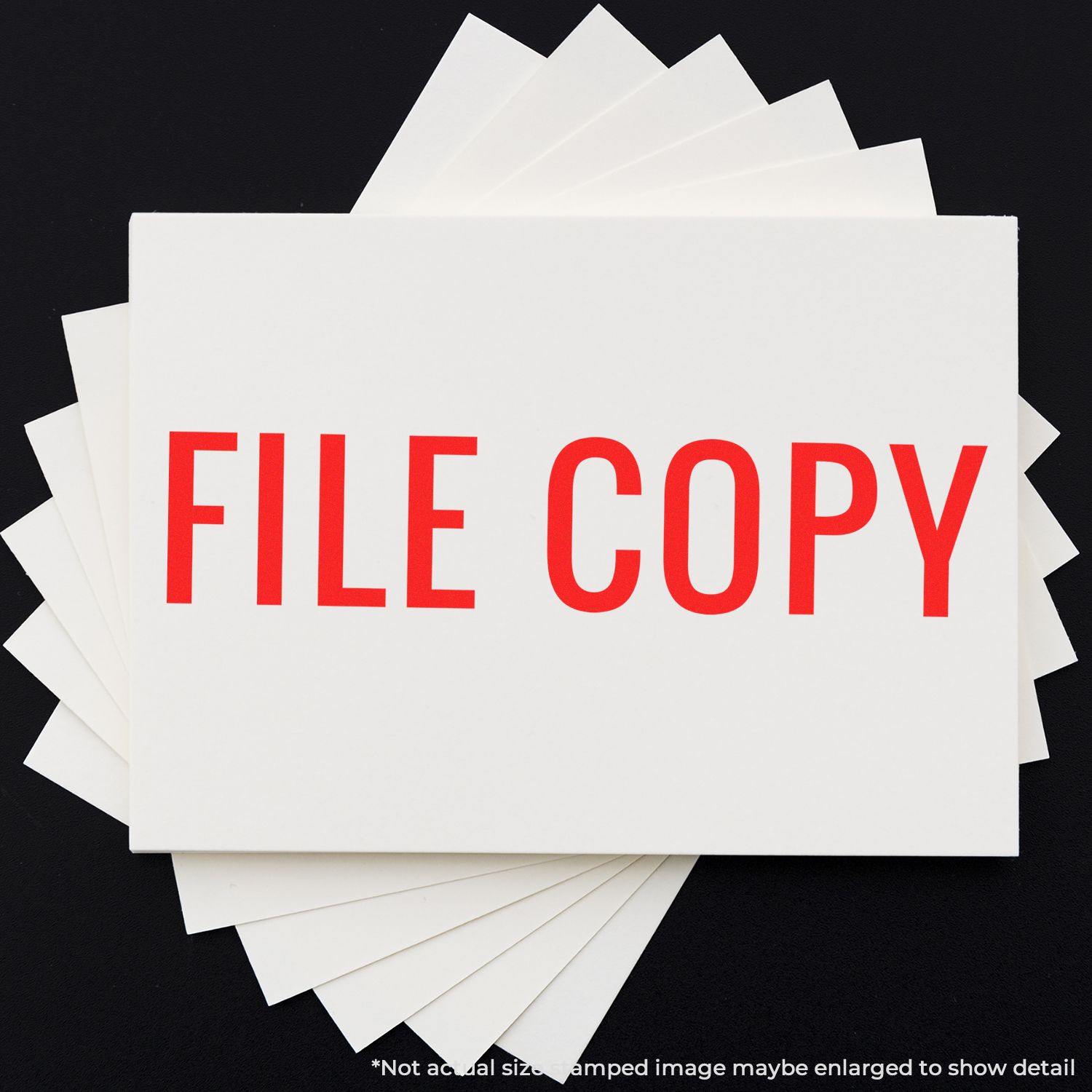 Large Pre-Inked Narrow Font File Copy Stamp in red ink on white paper, with multiple sheets underneath on a black background.